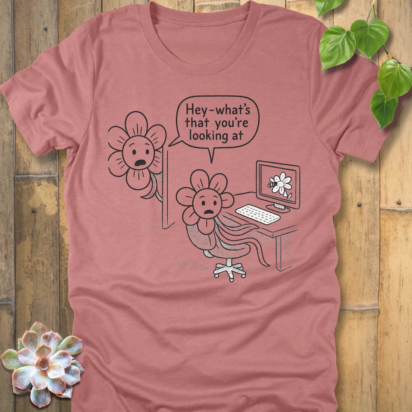 Heather mauve Bella+Canvas 3001 T-shirt with a black line drawing of two cartoon flowers. One flower is at a desk staring at a computer showing a flower image, while the other peeks from behind the monitor, surprised, saying ‘Hey—what’s that you’re looking at?’