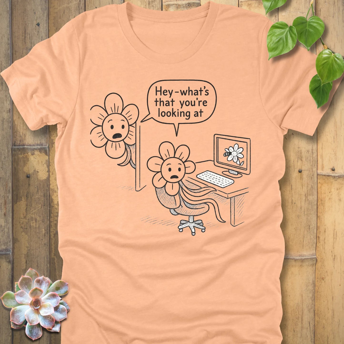 Heather peach Bella+Canvas 3001 T-shirt printed with a playful comic-style illustration of two flowers. One flower uses a computer, while another flower looks over the monitor, shocked, and asks ‘Hey—what’s that you’re looking at?