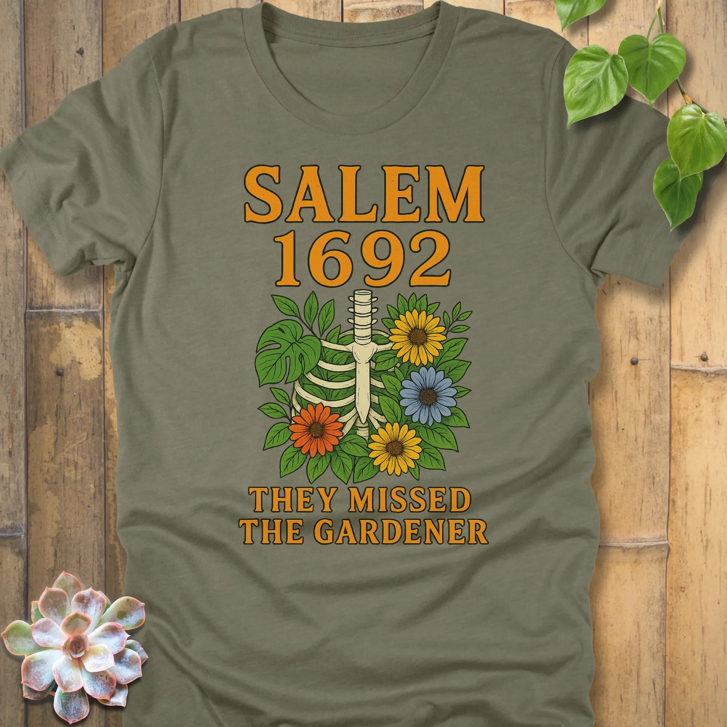 Heather Olive – Salem 1692 They Missed the Gardener T-shirt in Heather Olive, skeleton and floral print, premium Bella+Canvas 3001.
