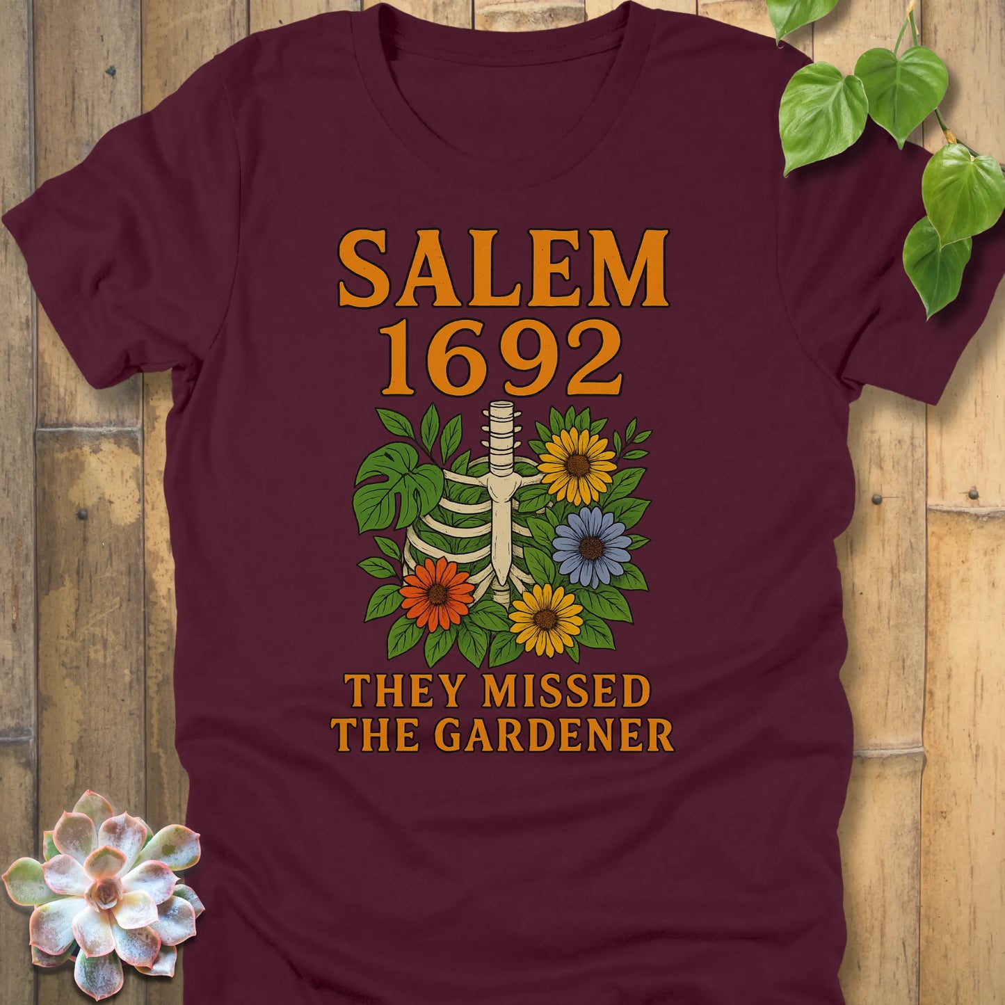 Maroon – Salem 1692 They Missed the Gardener T-shirt in Maroon, skeleton ribcage and floral bouquet graphic with orange text.