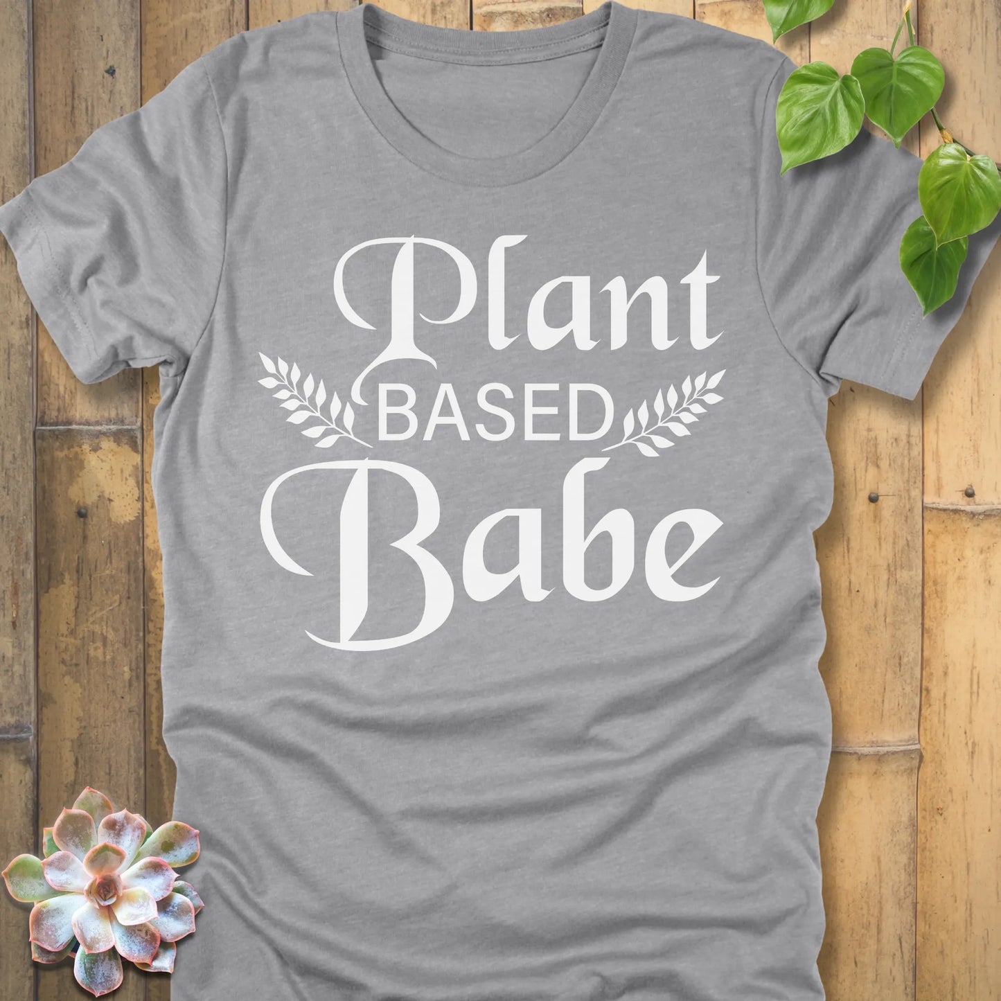 Athletic Heather t-shirt featuring the design Plant Based Babe printed in bold letters and a graphic leaves, vegan lifestyle shirt.