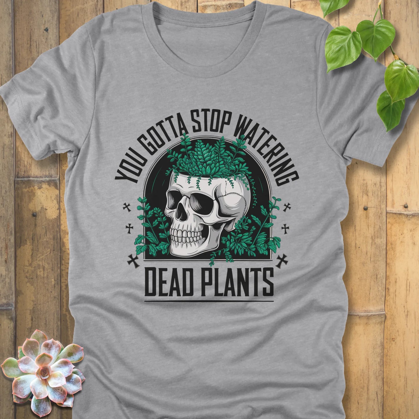 Athletic Heather t-shirt featuring the design âYou gotta stop watering dead plantsâ printed in black letters with skull and plants graphic