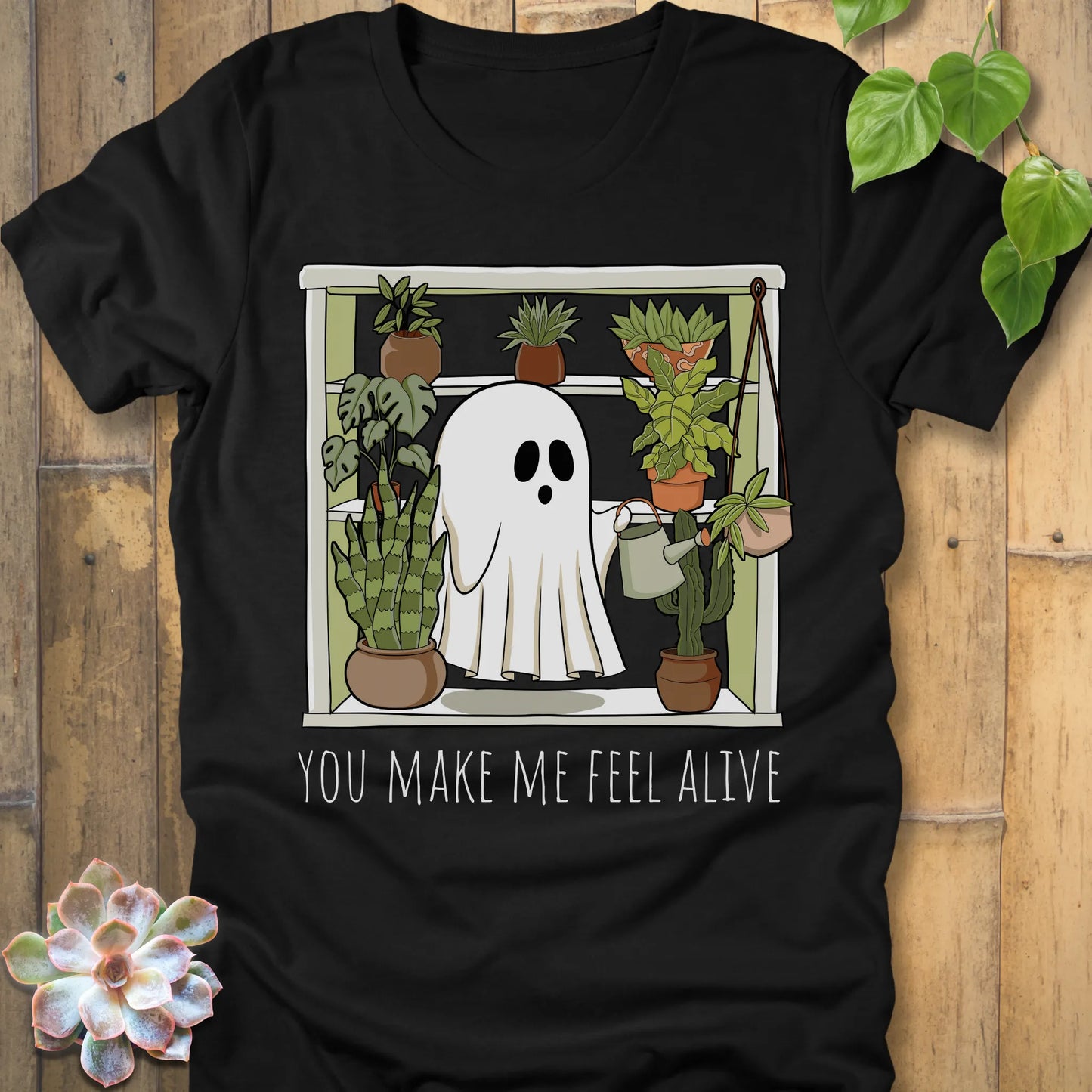 Black t-shirt featuring the design Make Me Feel Alive printed in bold white letters and a halloween ghost watering the plants design