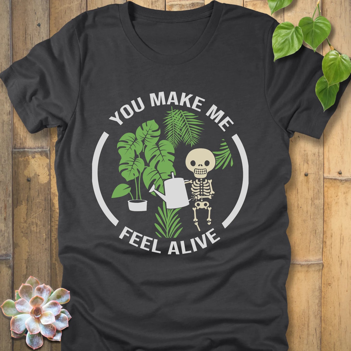 Dark Grey Heather t-shirt featuring the design You make me feel alive with plant and skeleton in bold white letters