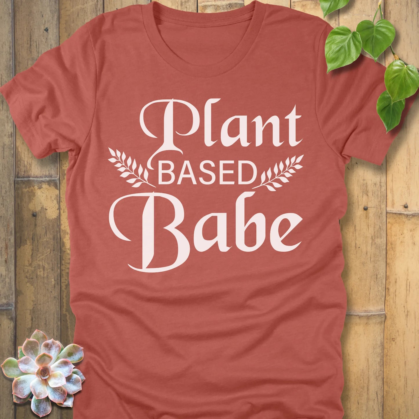 Heather Clay t-shirt featuring the design Plant Based Babe printed in bold letters and a graphic leaves, vegan lifestyle shirt.