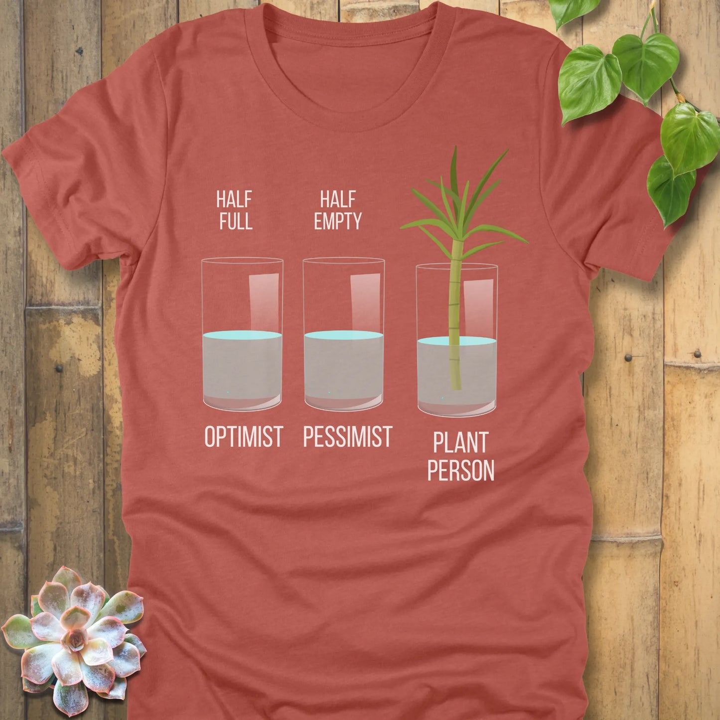 Heather Clay t-shirt featuring the design Plant Person printed in bold letters printed in glass of water, and a plant