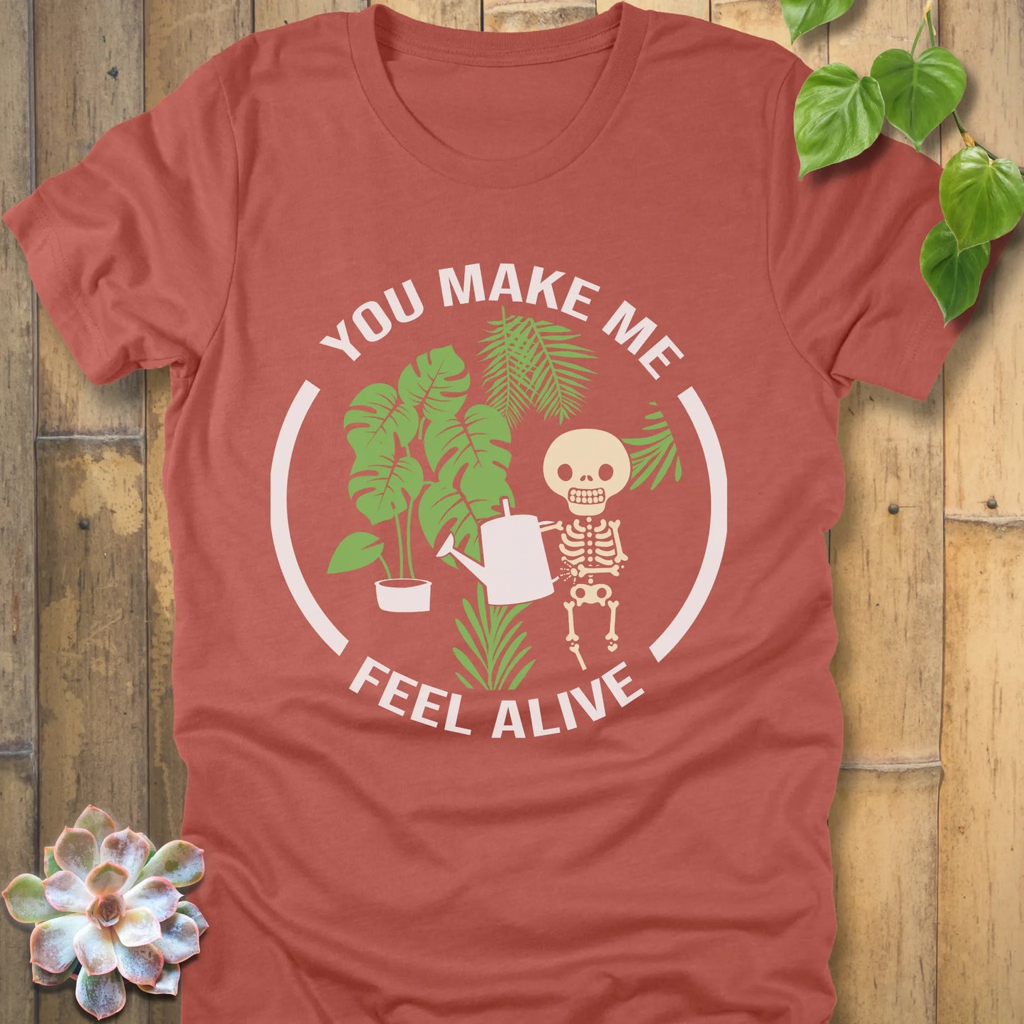Heather Clay t-shirt featuring the design You make me feel alive with plant and skeleton in bold white letters