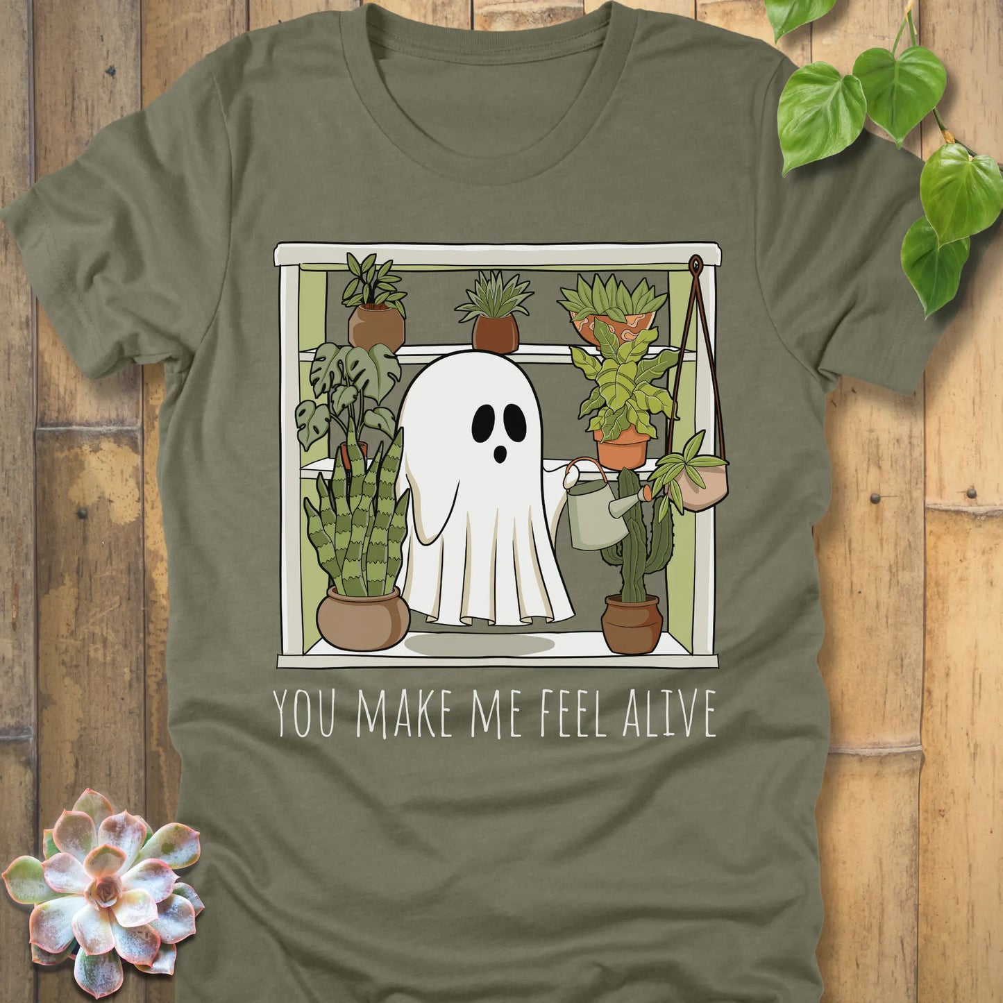 Heather Olive t-shirt featuring the design Make Me Feel Alive printed in bold white letters and a halloween ghost watering the plants design