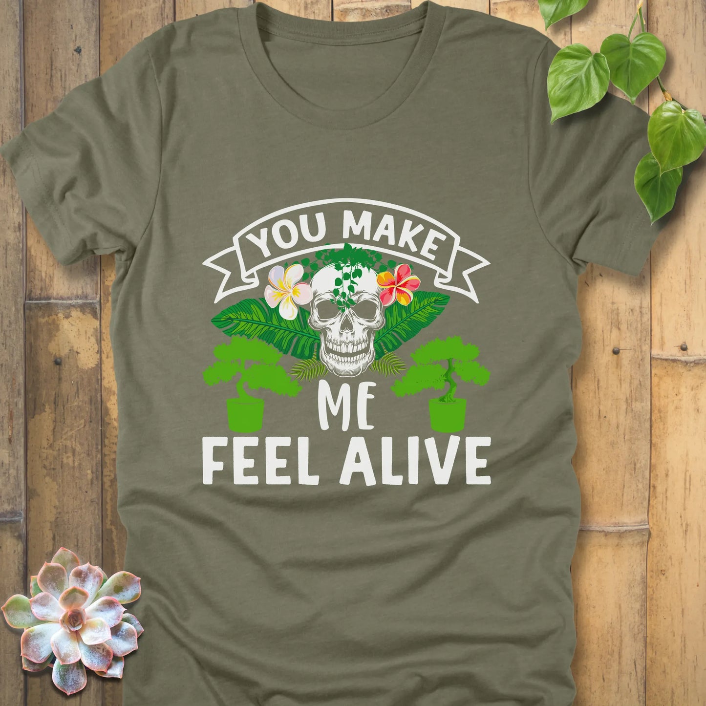 Heather Olive t-shirt featuring the design You Make Me Feel Alive printed in bold white letters with skull and plants