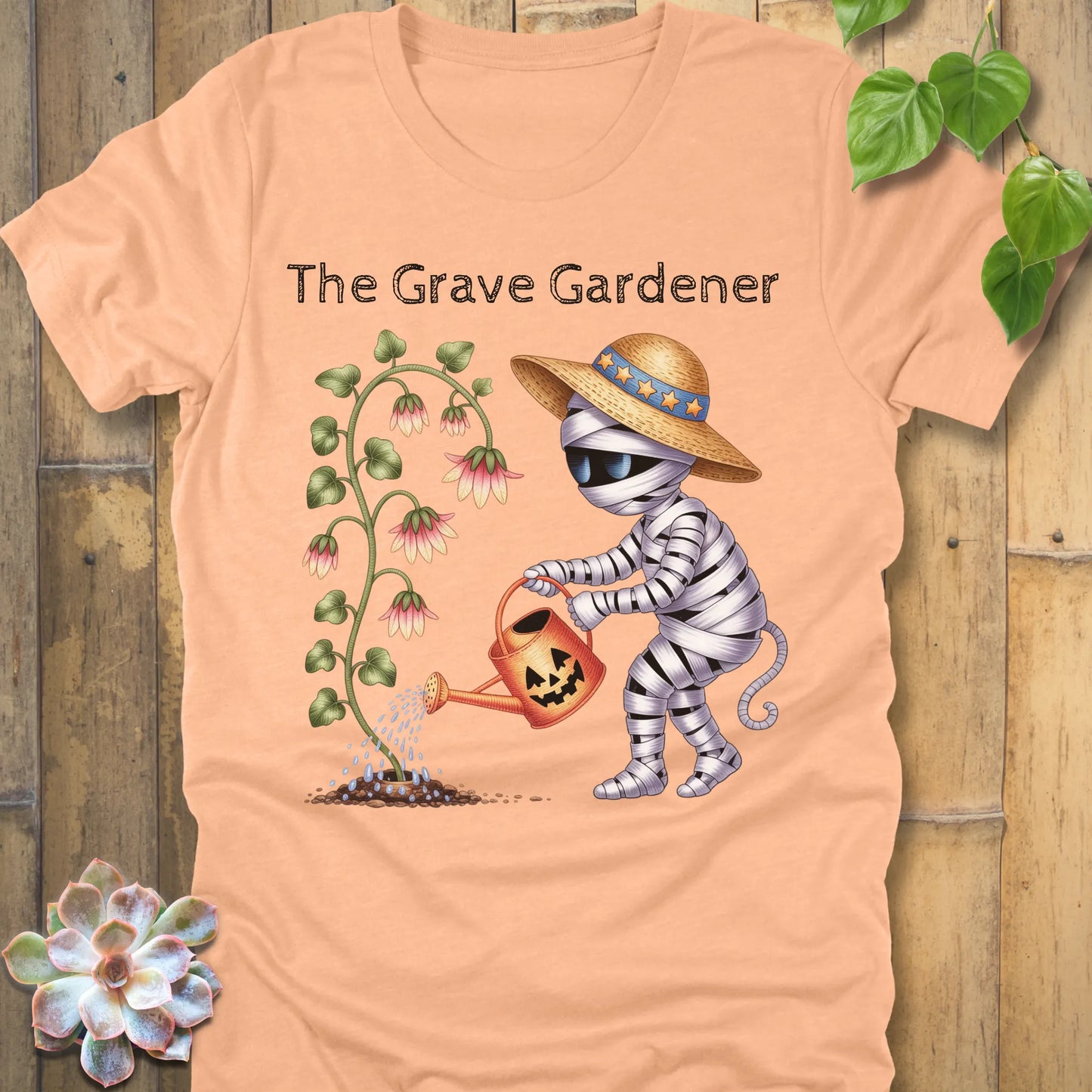Heather Peach t-shirt featuring the design The Grave Gardener printed in bold black letters and a ghost watering the plant