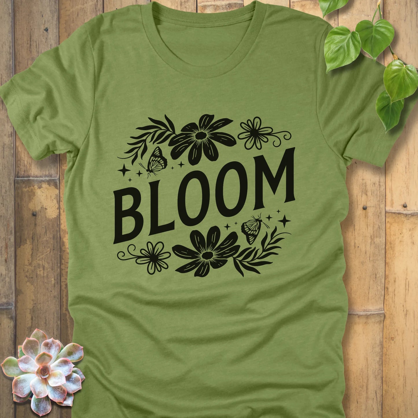 Heather green t-shirt featuring the design " Bloom " printed in bold black letters with flowers