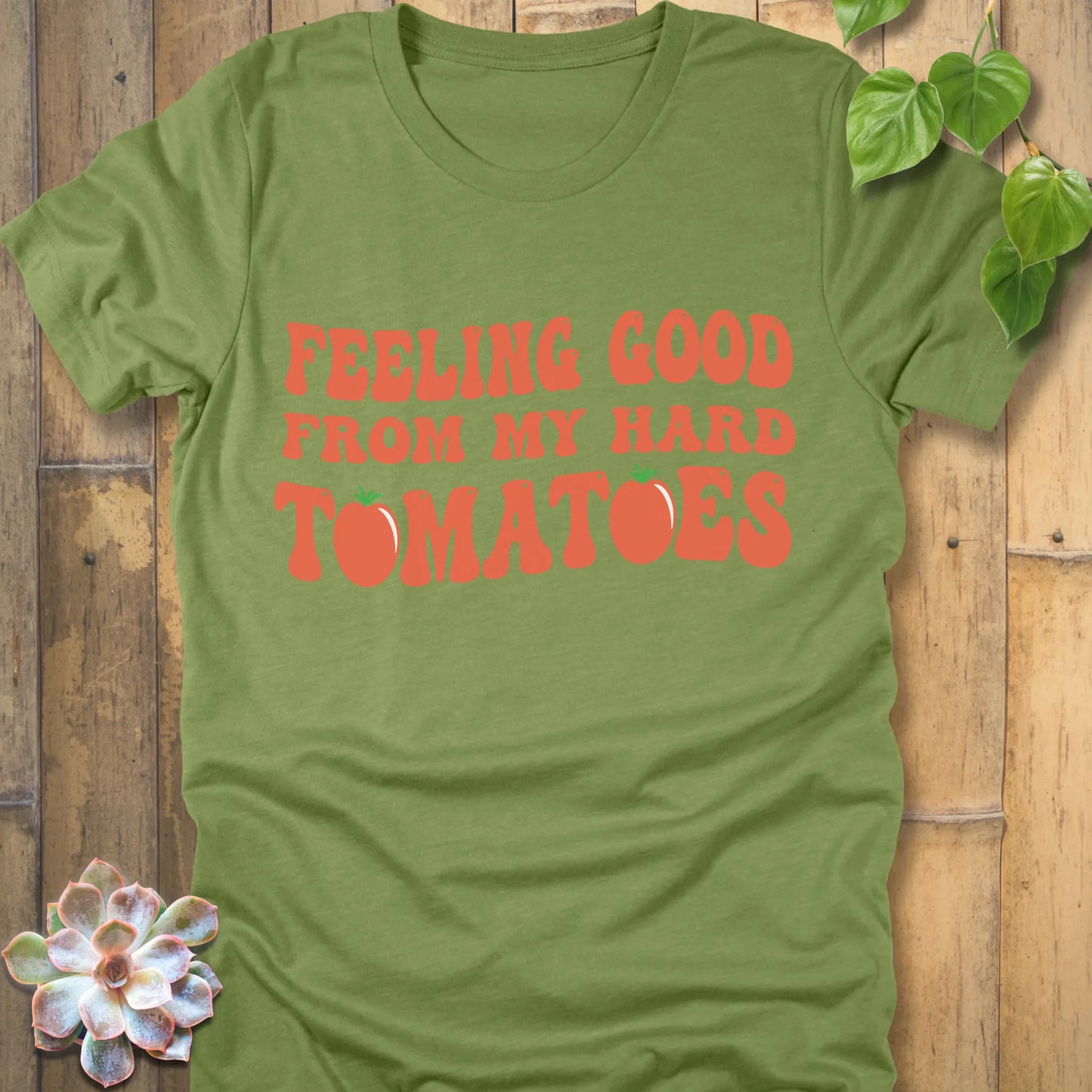 Heather green t-shirt featuring the design "Feeling Good from my hard tomatoes" printed in bold orange letters