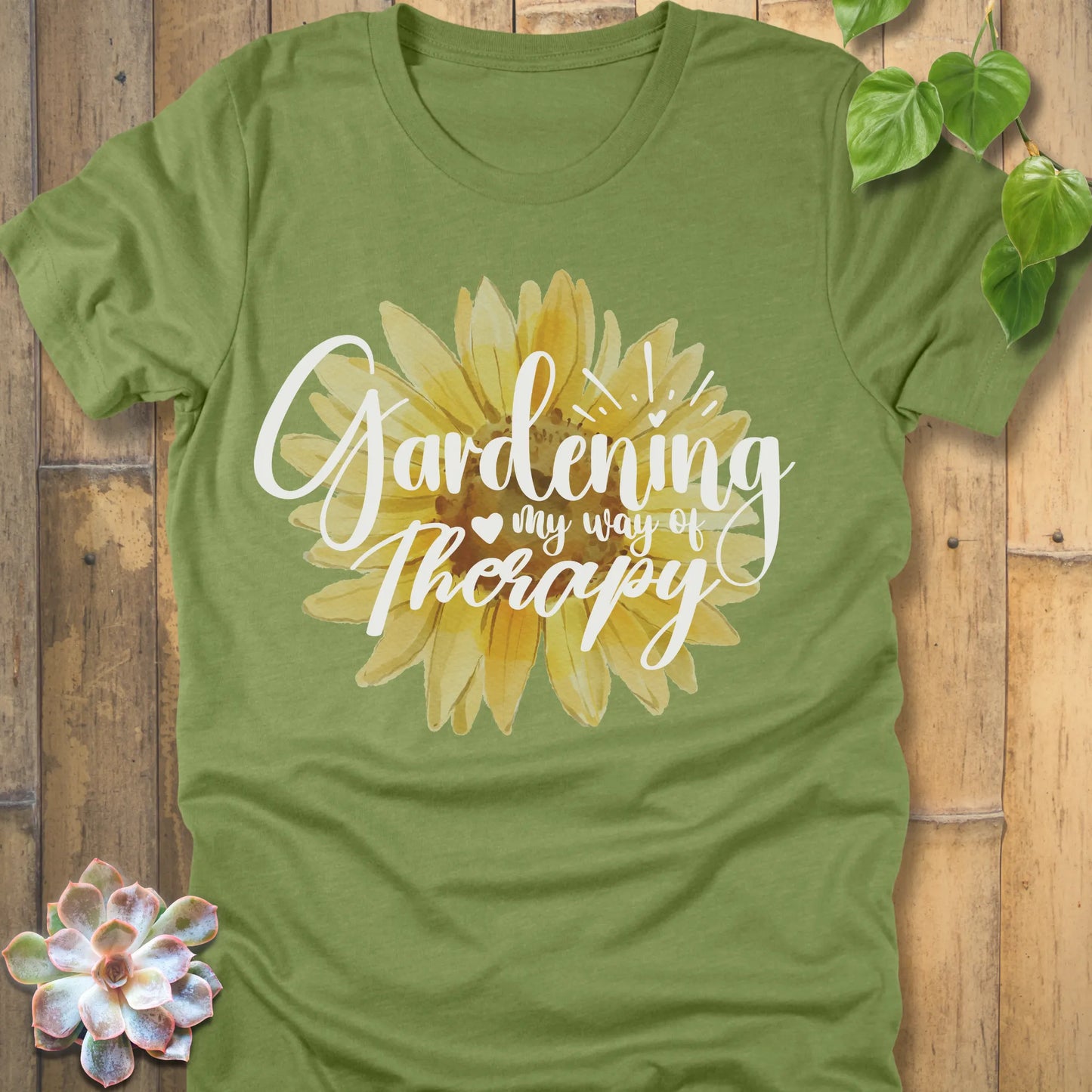 Heather green t-shirt featuring the design Gardening my way of therapy with a sunflower in the center.