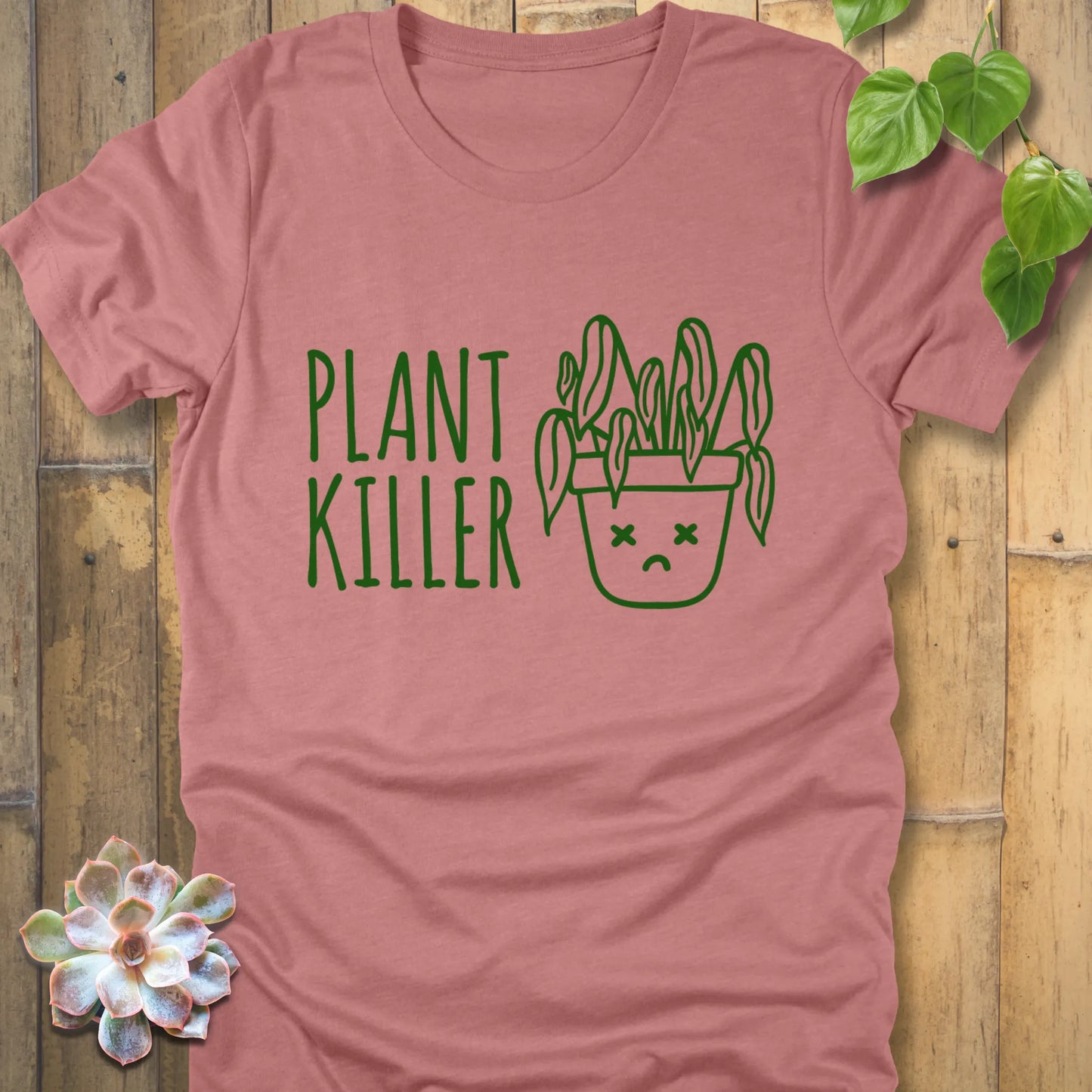 Heather mauve t-shirt featuring the design Plant Killer printed in green letters with a plant in an emoji pot