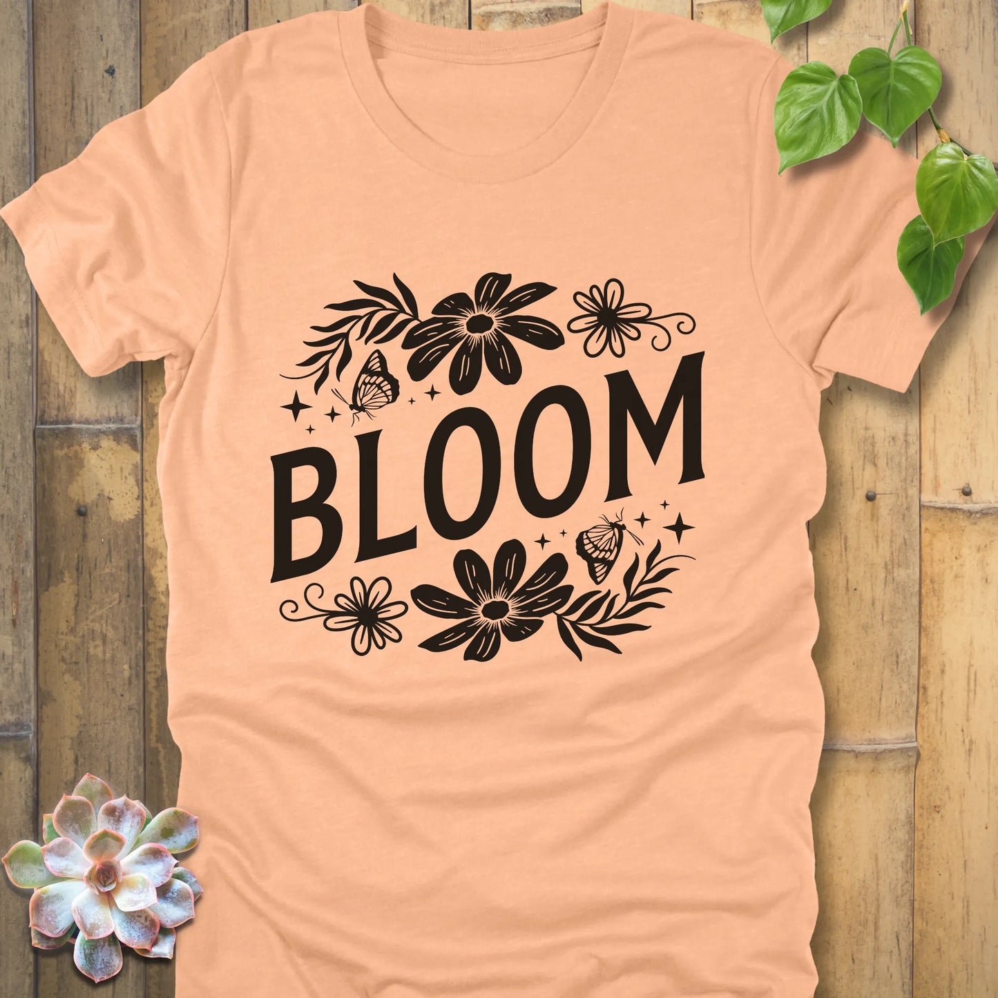 Heather peach t-shirt featuring the design " Bloom " printed in bold black letters with flowers
