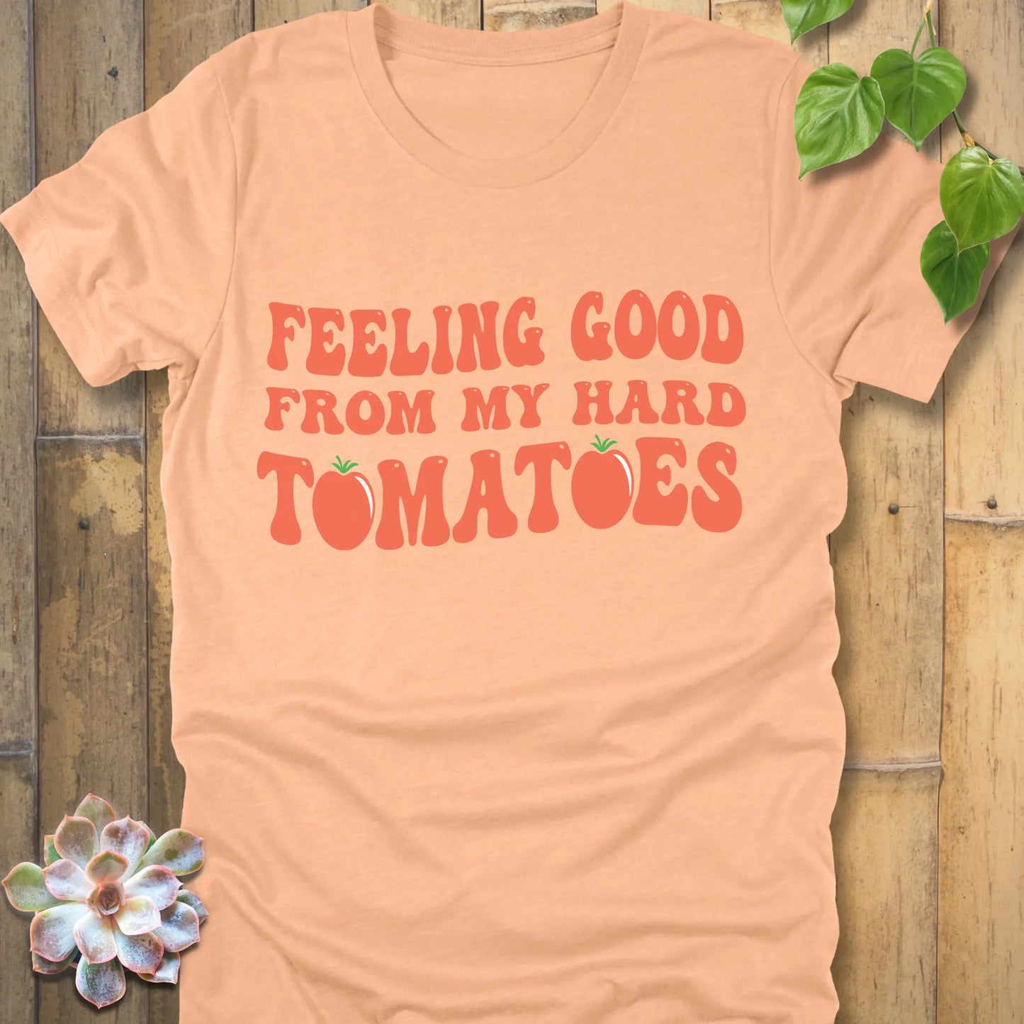 Heather peach t-shirt featuring the design "Feeling Good from my hard tomatoes" printed in bold orange letters, heather peach cotton tee.
