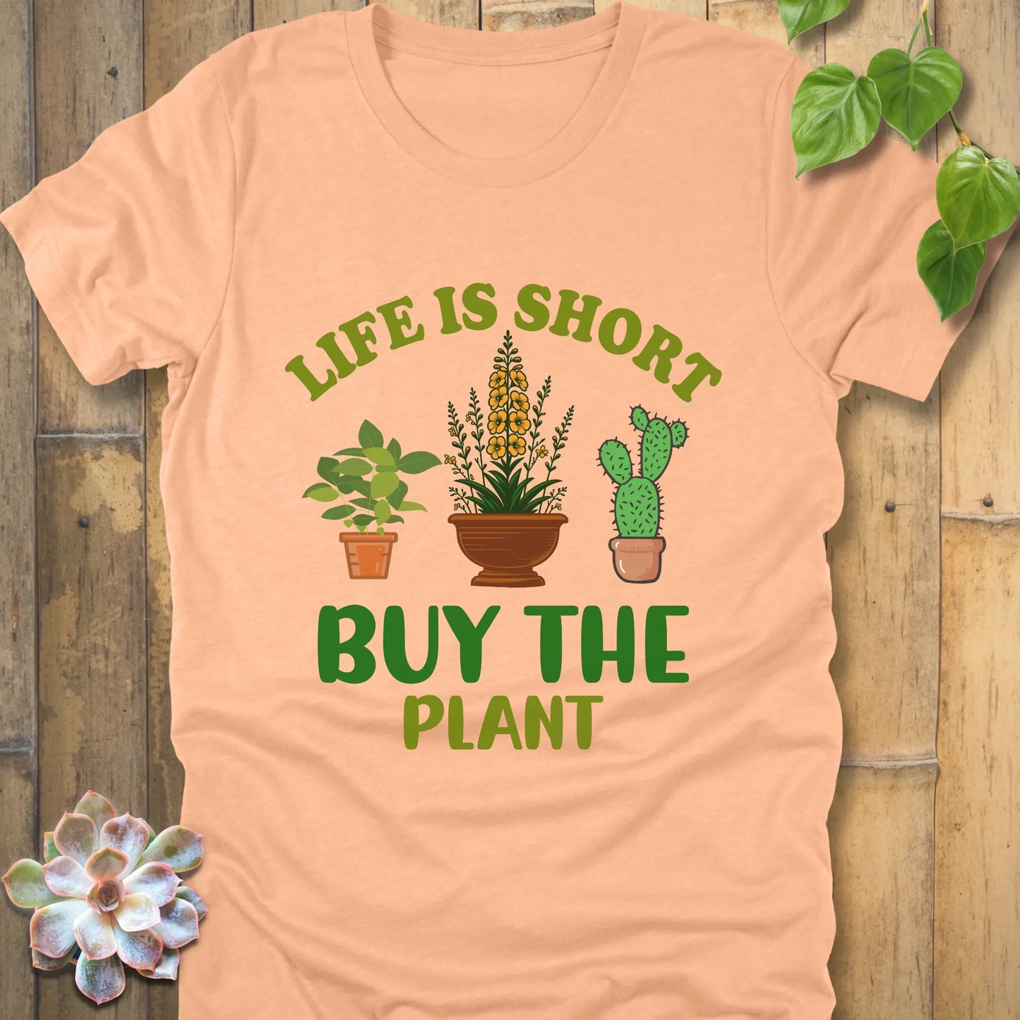Heather peach t-shirt featuring the design Life is short, buy the plant printed in green text with plant illustration