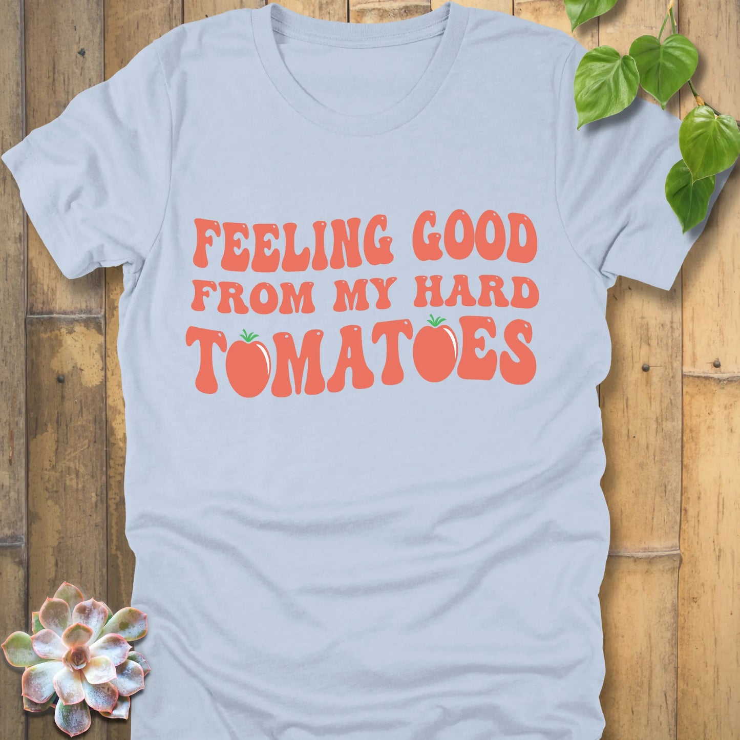 Light blue t-shirt featuring the design "Feeling Good from my hard tomatoes" printed in bold orange letters