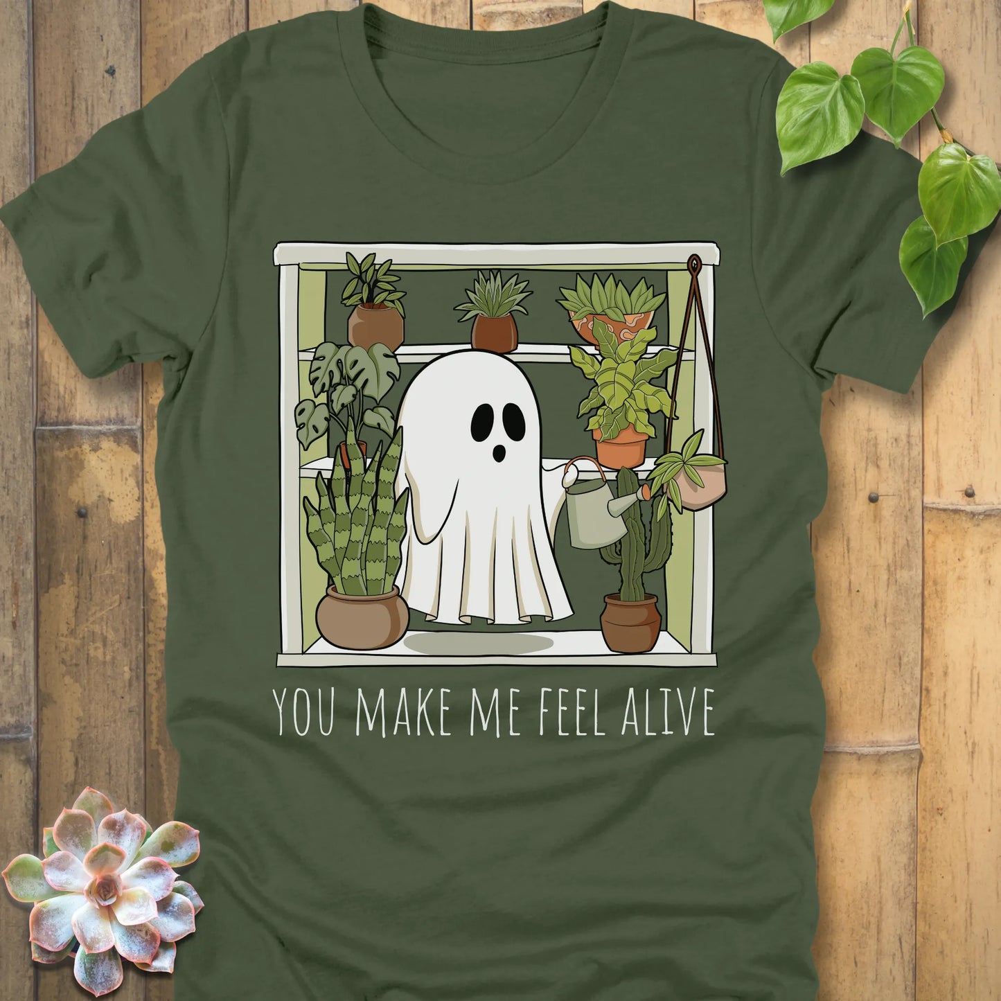 Military Green t-shirt featuring the design Make Me Feel Alive printed in bold white letters and a halloween ghost watering the plants design
