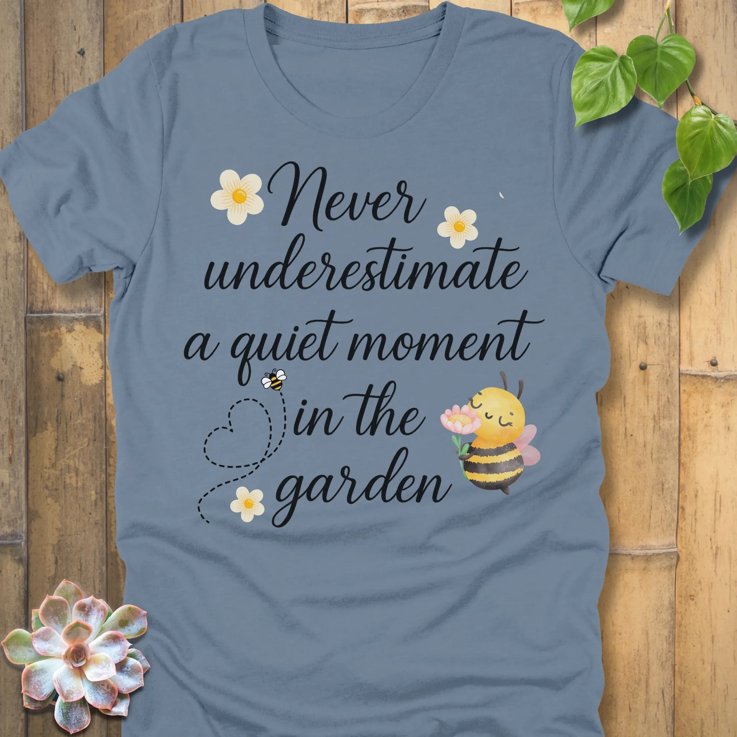 Steel Blue t-shirt featuring the design Never Underestimate printed in black letters, empowering quote shirt.