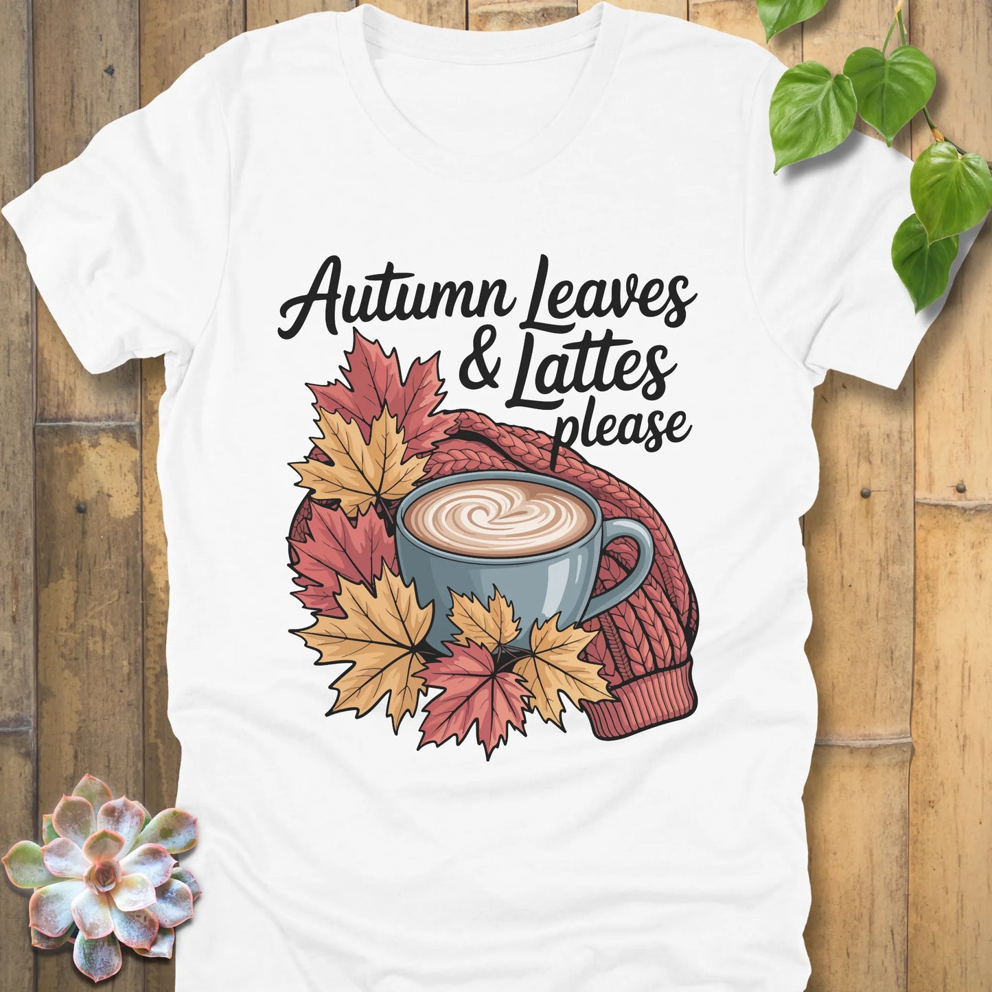 White t-shirt featuring the design Autumn Leaves & Lattes printed in black letters with a mug of coffee and leaves