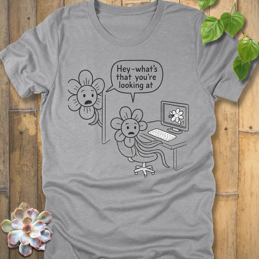 Athletic heather grey Bella+Canvas 3001 T-shirt decorated with a humorous cartoon. A flower character sits at a computer, staring at a screen showing a flower image. Another flower peers from behind the monitor and says, ‘Hey—what’s that you’re looking at?
