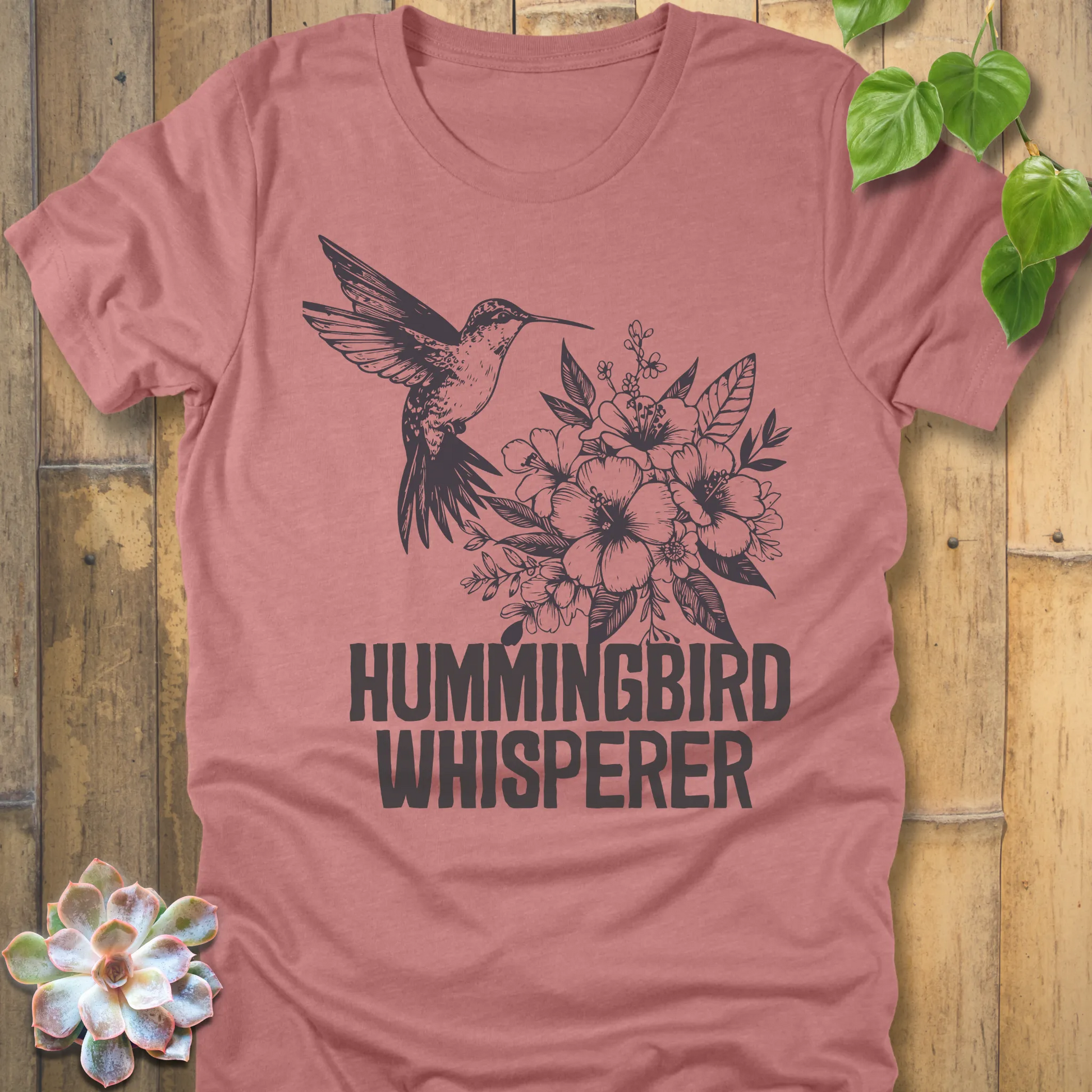 Heather mauve “Hummingbird Whisperer” T-shirt with a black floral and hummingbird print, stylish nature-inspired design on a soft cotton-blend shirt