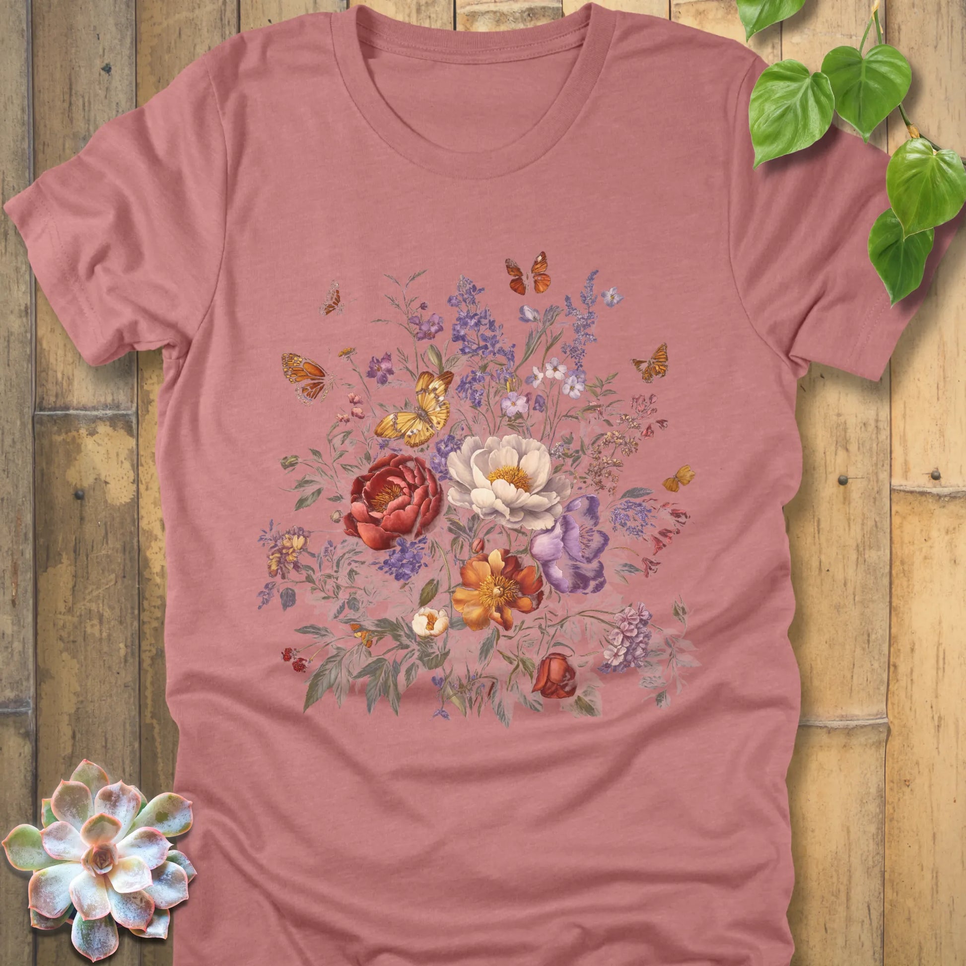 Heather Mauve t-shirt decorated with a large floral design of red, white, orange, and purple flowers with butterflies flying around