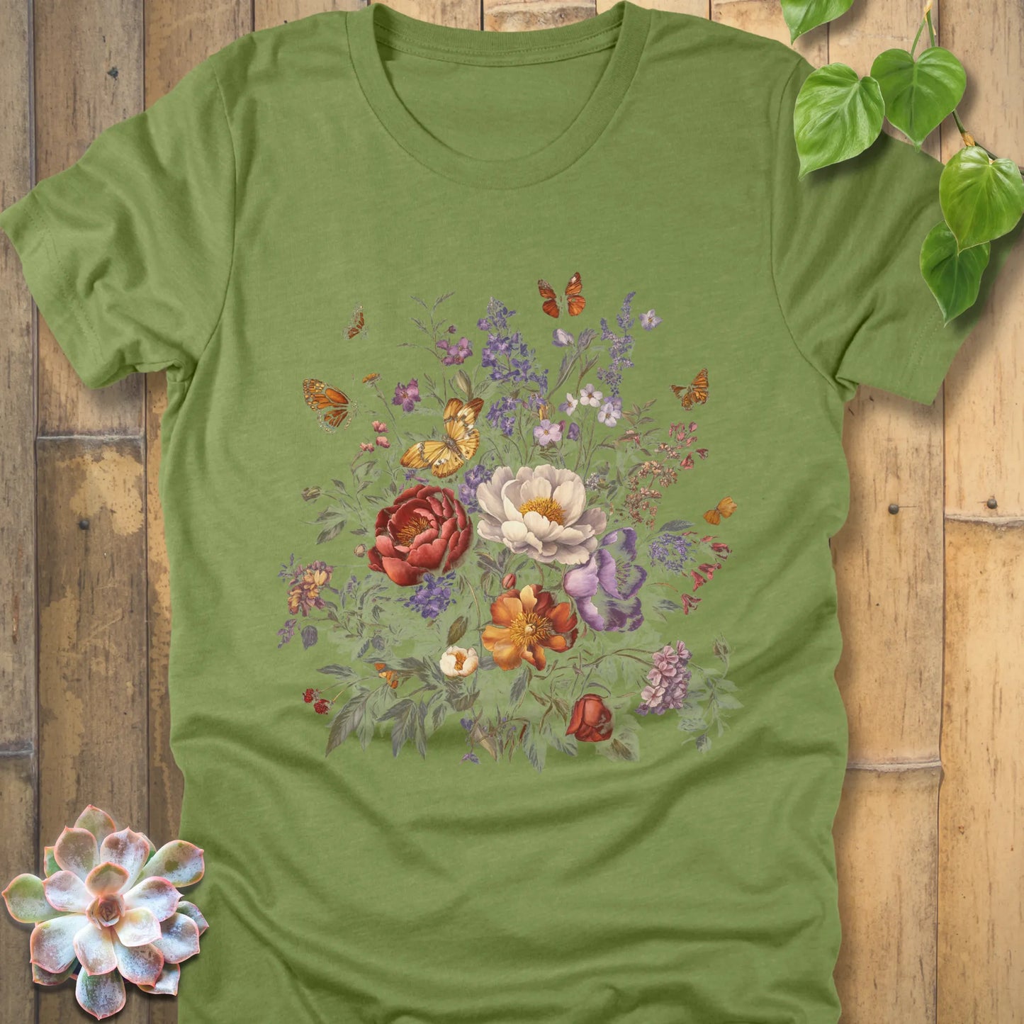 Heather Green t-shirt showcasing a vibrant floral bouquet with red, white, orange, and purple blossoms surrounded by butterflies.