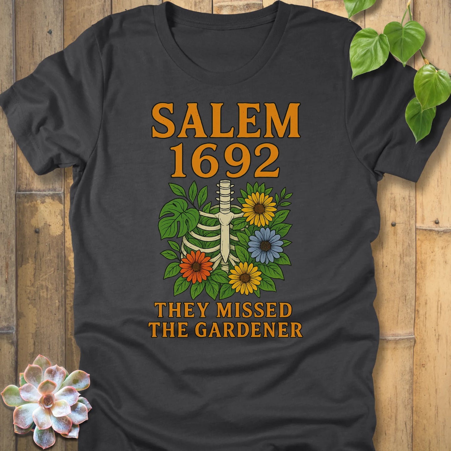 Dark Heather Grey – Salem 1692 They Missed the Gardener T-shirt in Dark Heather Grey, ribcage floral design with orange lettering.