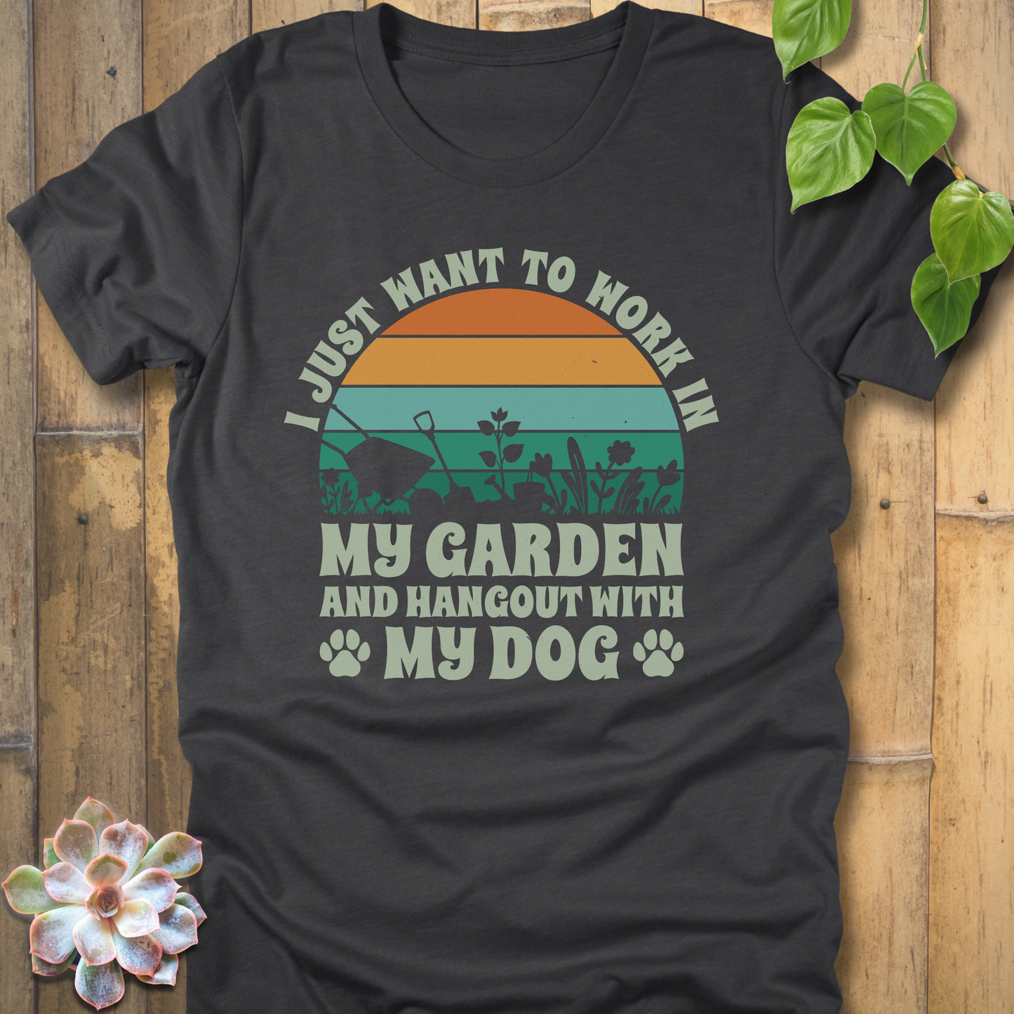 Dark Grey Heather novelty t-shirt featuring a vintage-style sunset graphic and the words I just want to work in my garden and hang out with my dog, with paw prints and garden silhouettes