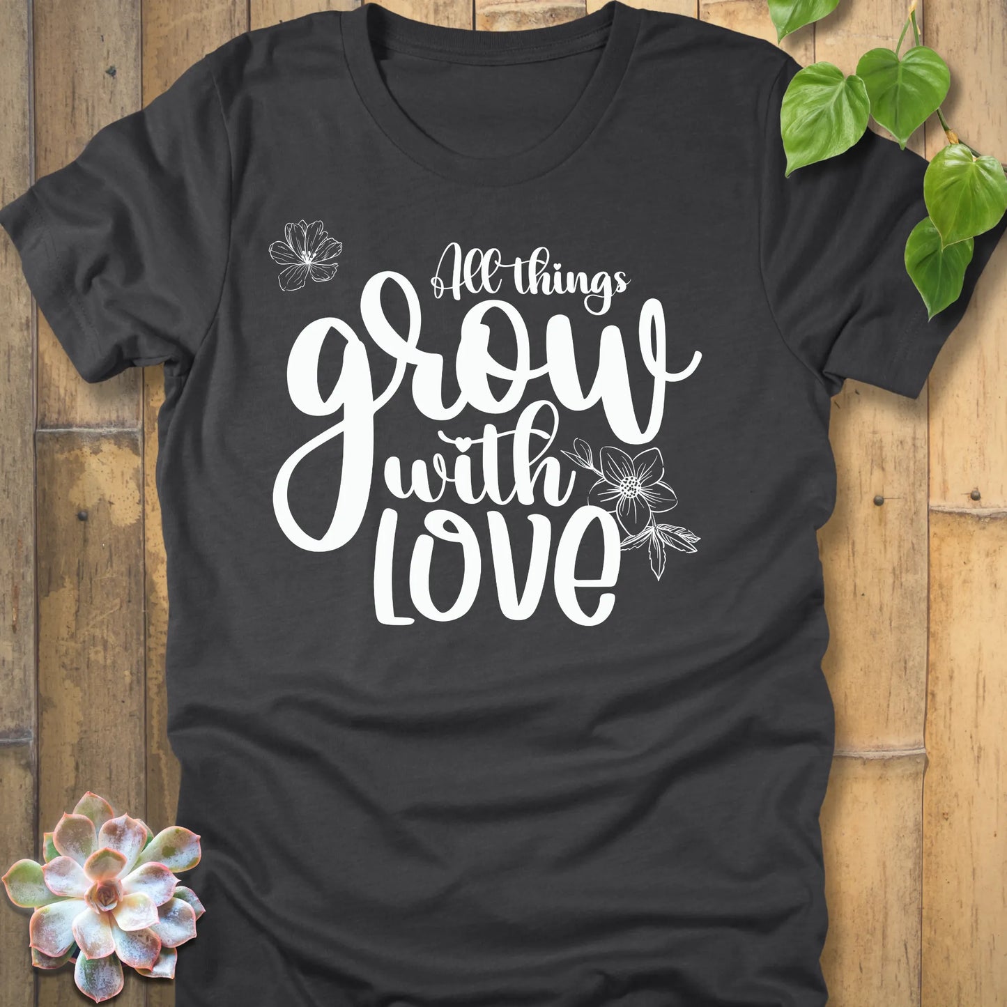 Dark grey heather unisex T-shirt featuring the inspirational quote ‘All things grow with love’ in bold white script with floral line art