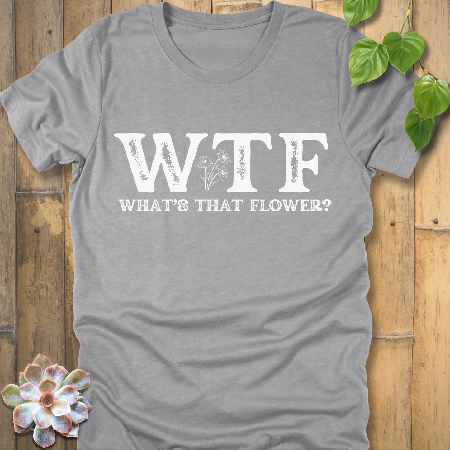 Athletic Heather t-shirt with bold white text reading WTF, What’s That Flower, featuring a small floral illustration