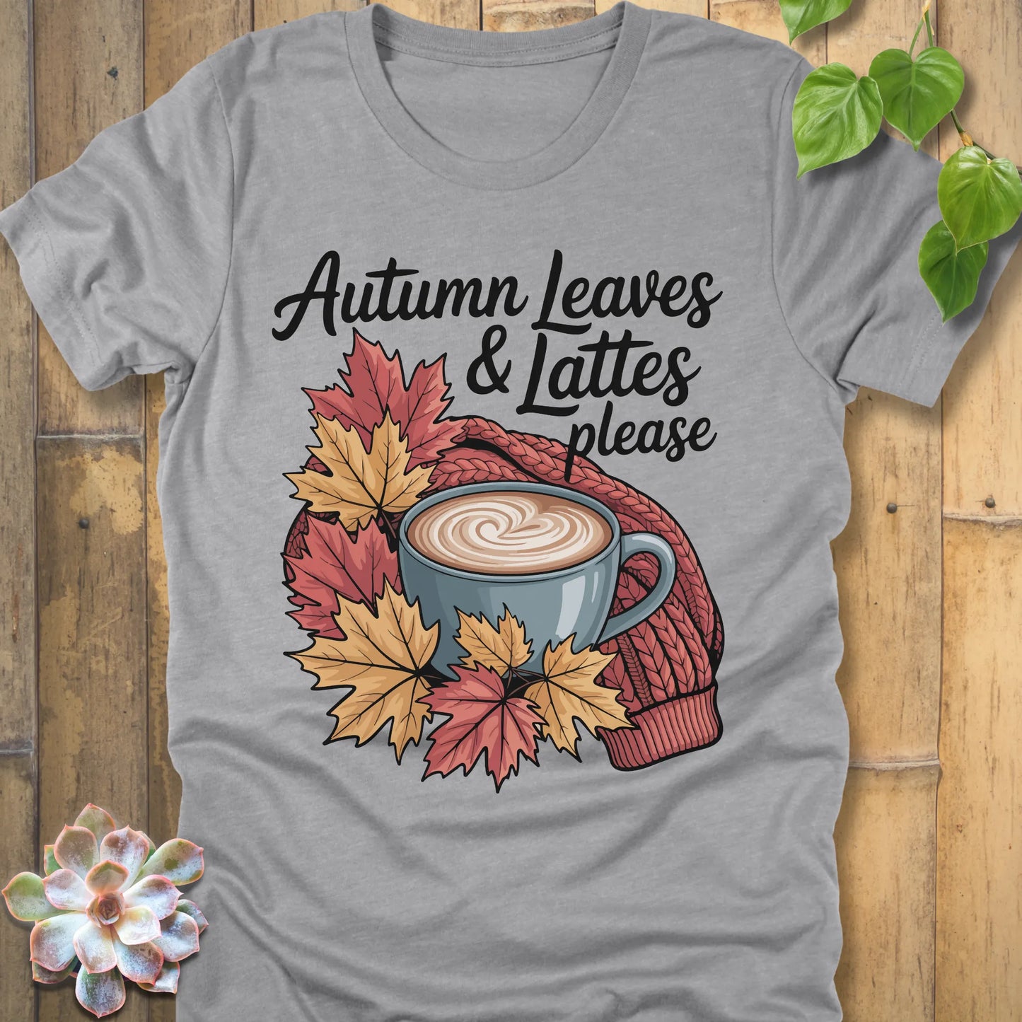 Athletic Heather t-shirt featuring the design Autumn Leaves & Lattes printed in black letters with a mug of coffee and leaves
