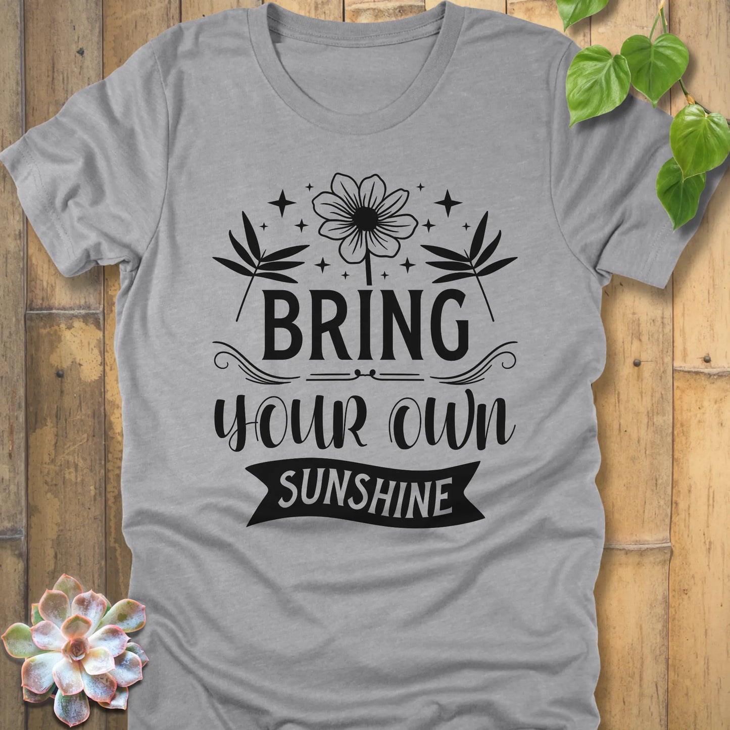Athletic Heather t-shirt featuring the design "Bring Your Own Sunshine" printed in black lette and flower