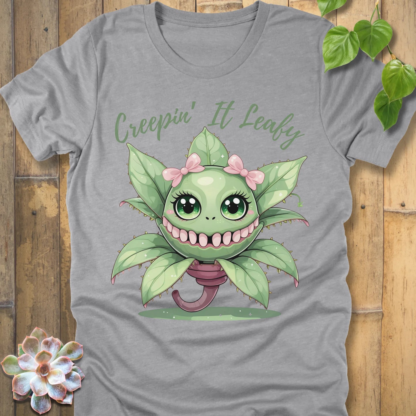 Athletic Heather t-shirt featuring the design Creepin' It Leafy printed in green letters and a happy plant