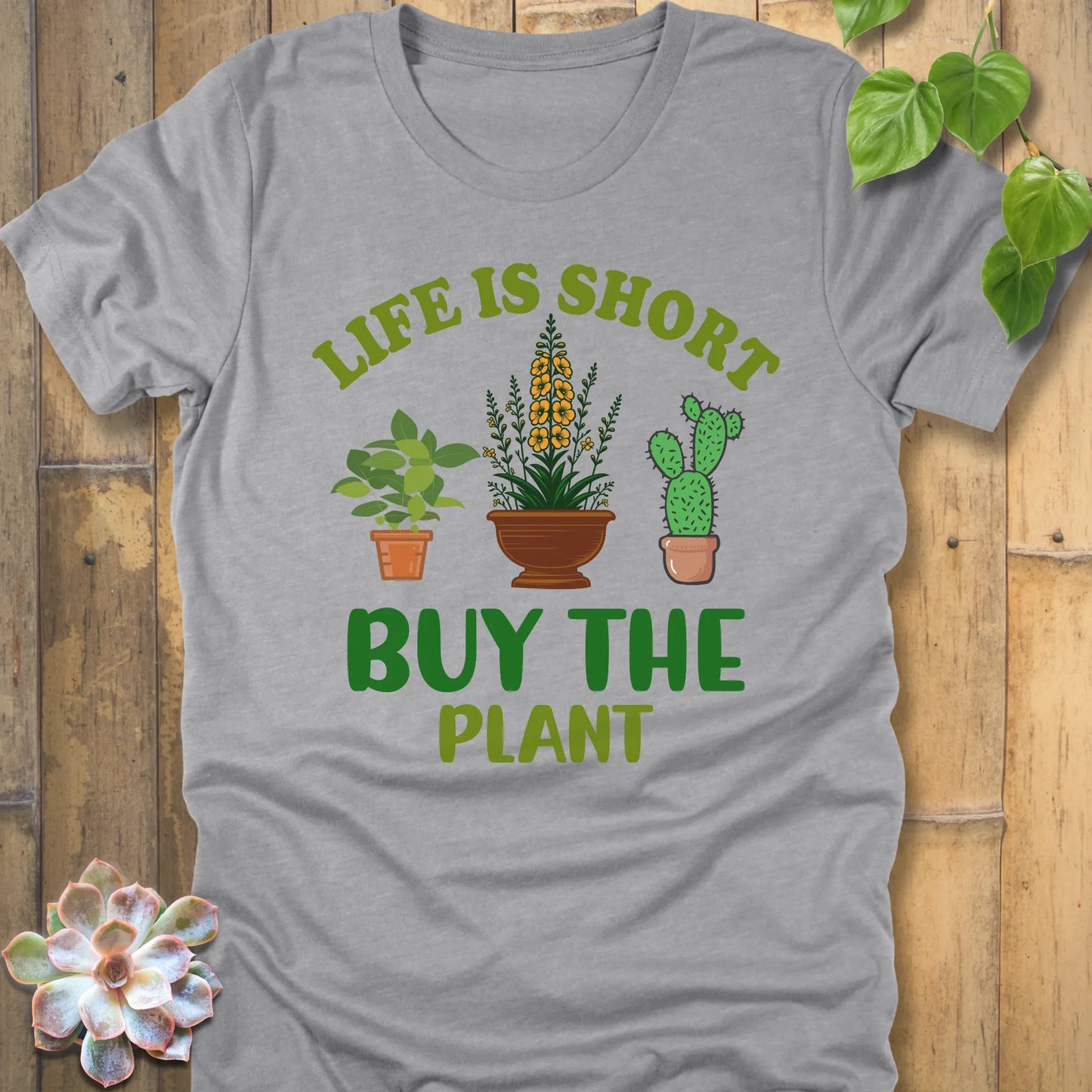 Athletic Heather t-shirt featuring the design Life is short, buy the plant printed in green text with plant illustration