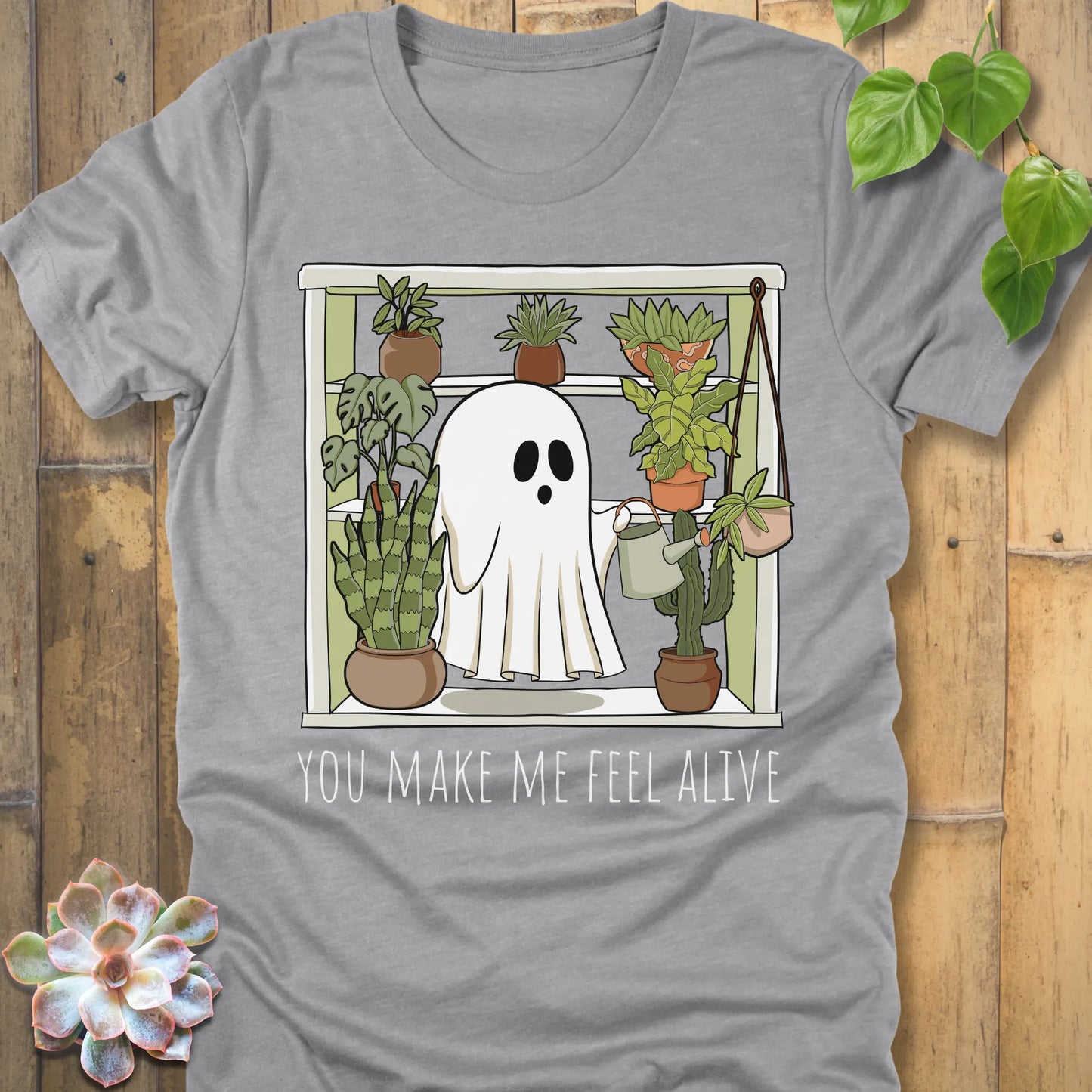 Athletic Heather t-shirt featuring the design Make Me Feel Alive printed in bold white letters and a halloween ghost watering the plants design