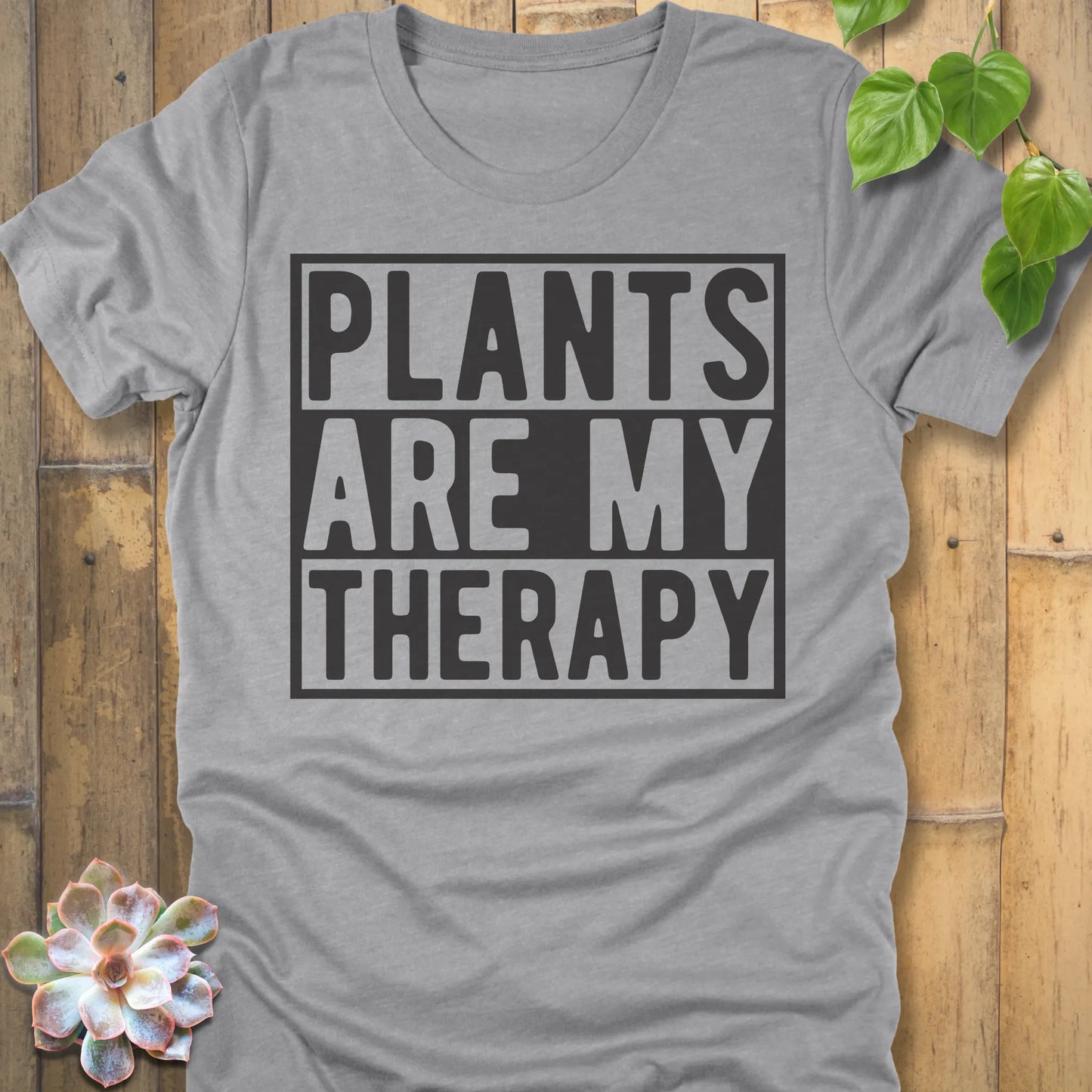 Athletic Heather t-shirt featuring the design Plants Are My Therapy printed in bold letters, plant lover shirt.