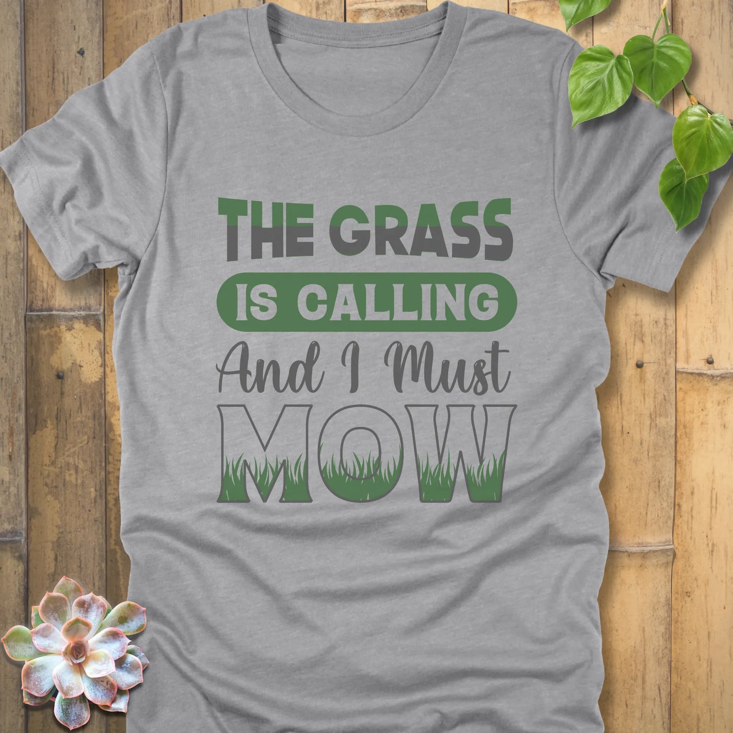 Athletic Heather t-shirt featuring the design The Grass is Calling and I Must Mow in bold letters and with grass