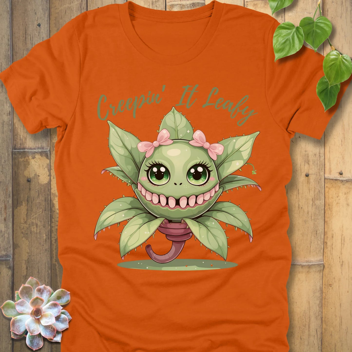 Autumn t-shirt featuring the design Creepin' It Leafy printed in green letters and a happy plant