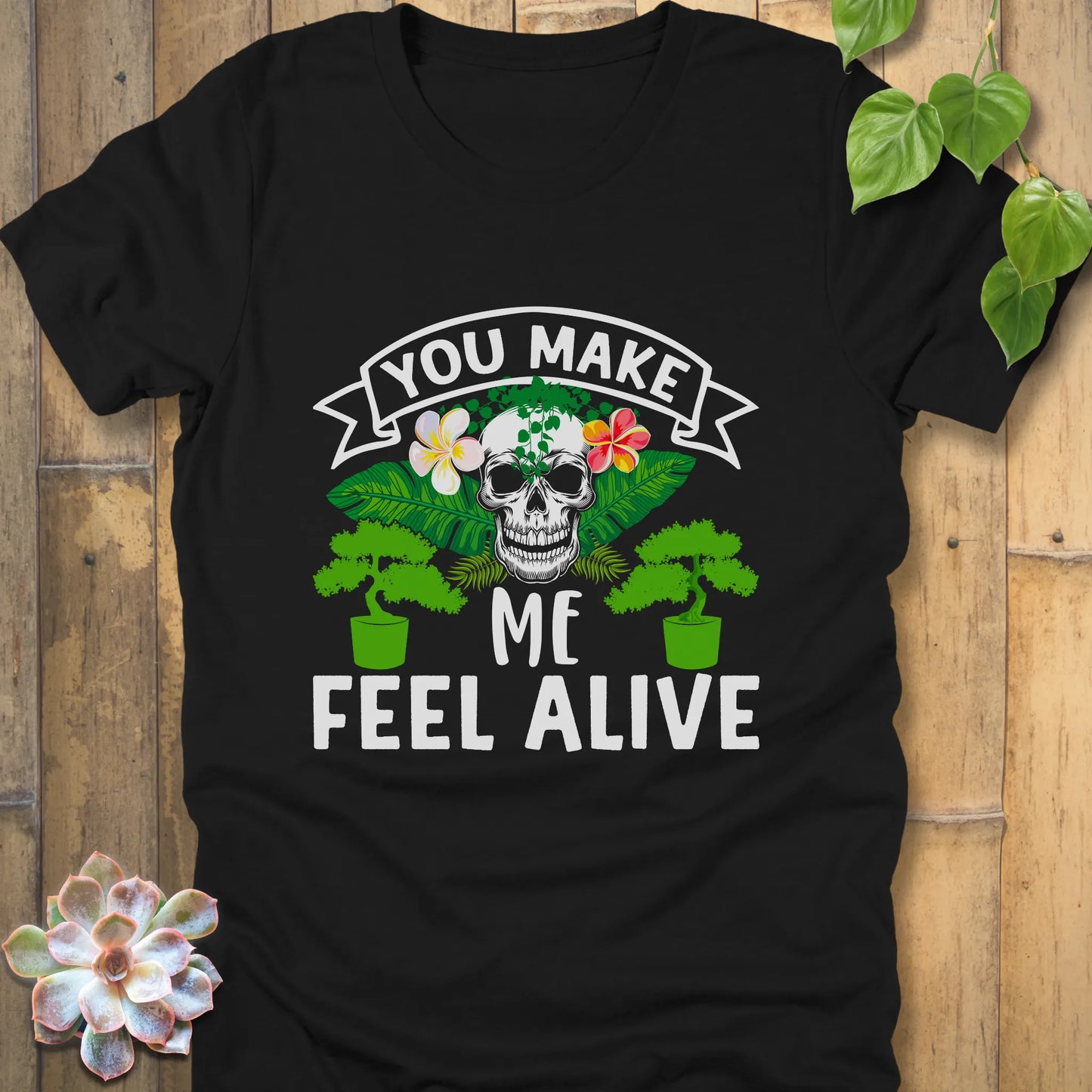 Black t-shirt featuring the design You Make Me Feel Alive printed in bold white letters with skull and plants