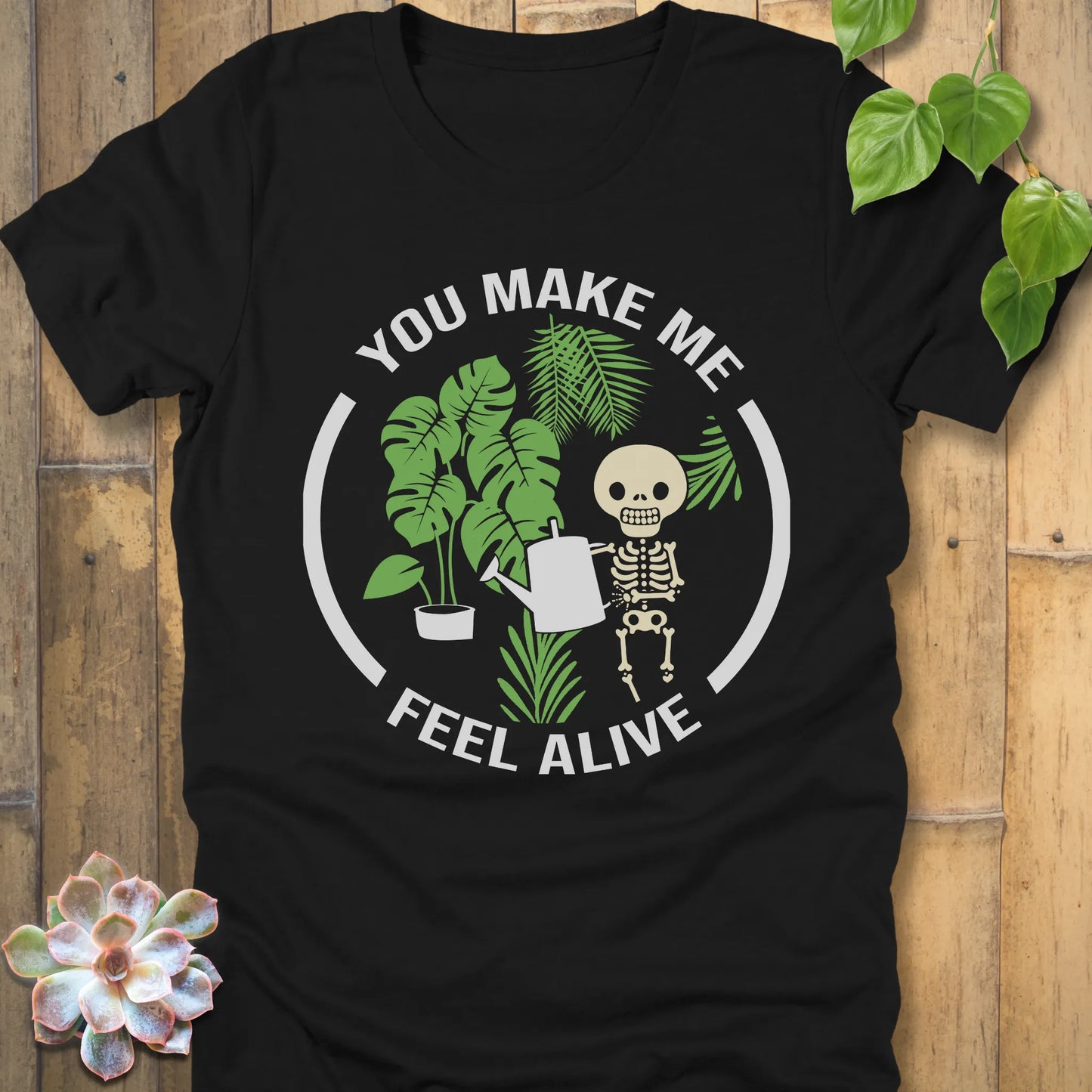 Black t-shirt featuring the design You make me feel alive with plant and skeleton in bold white letters