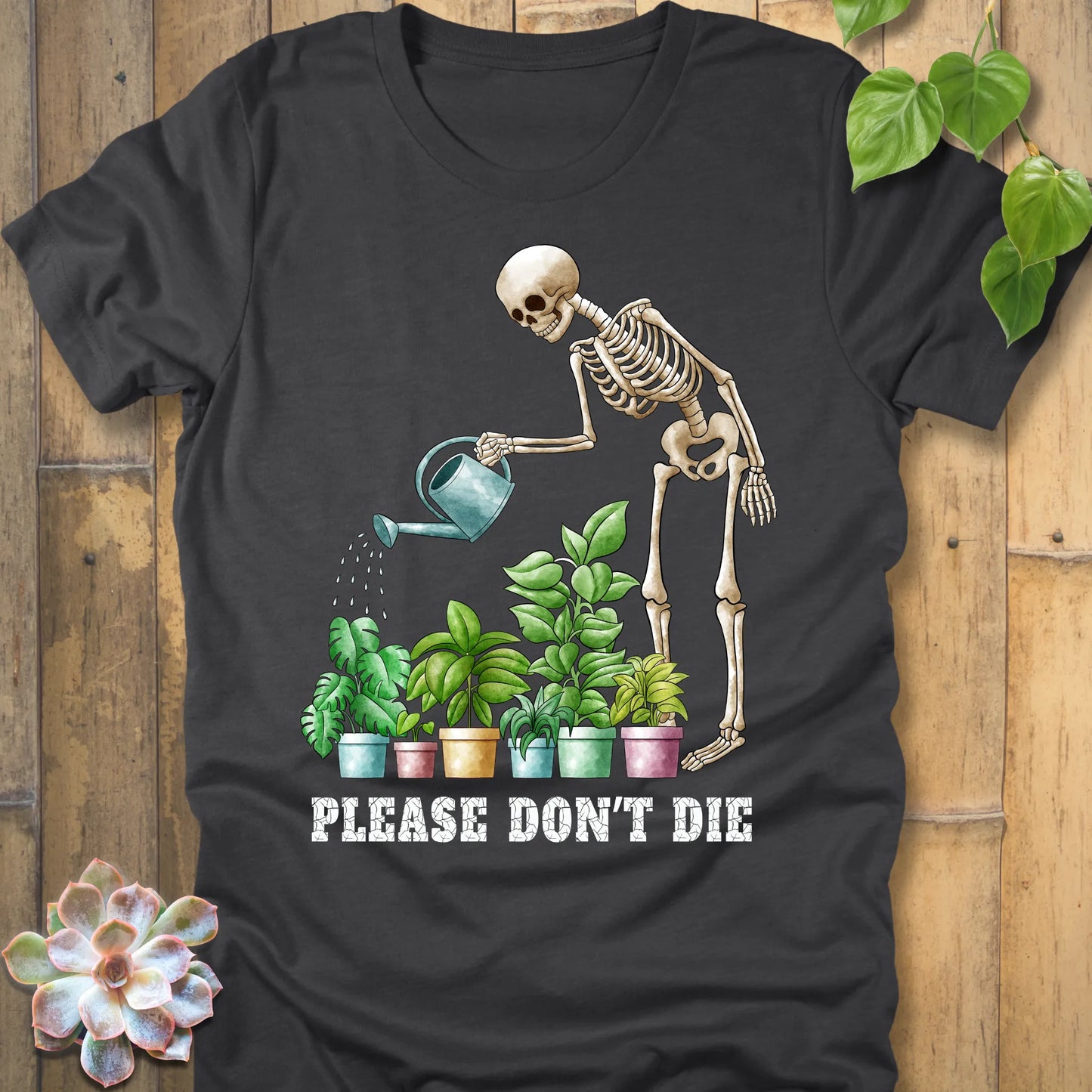 Dark grey heather t-shirt featuring the design Please Don’t Die with skeleton watering plants print