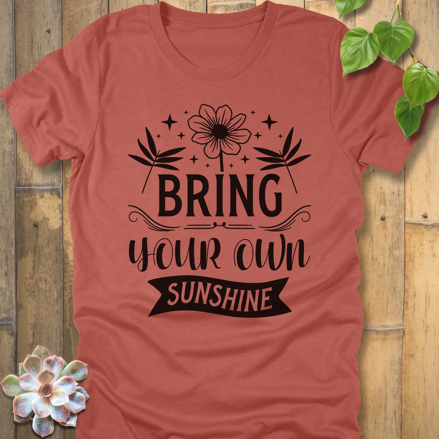 Heather Clay t-shirt featuring the design "Bring Your Own Sunshine" printed in black lette and flower