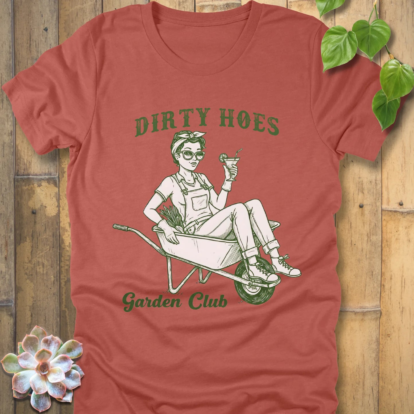 Heather Clay t-shirt featuring the design Dirty Hoes, Garden Club printed in green letters with a girl in the trolley, gardening graphic tee.