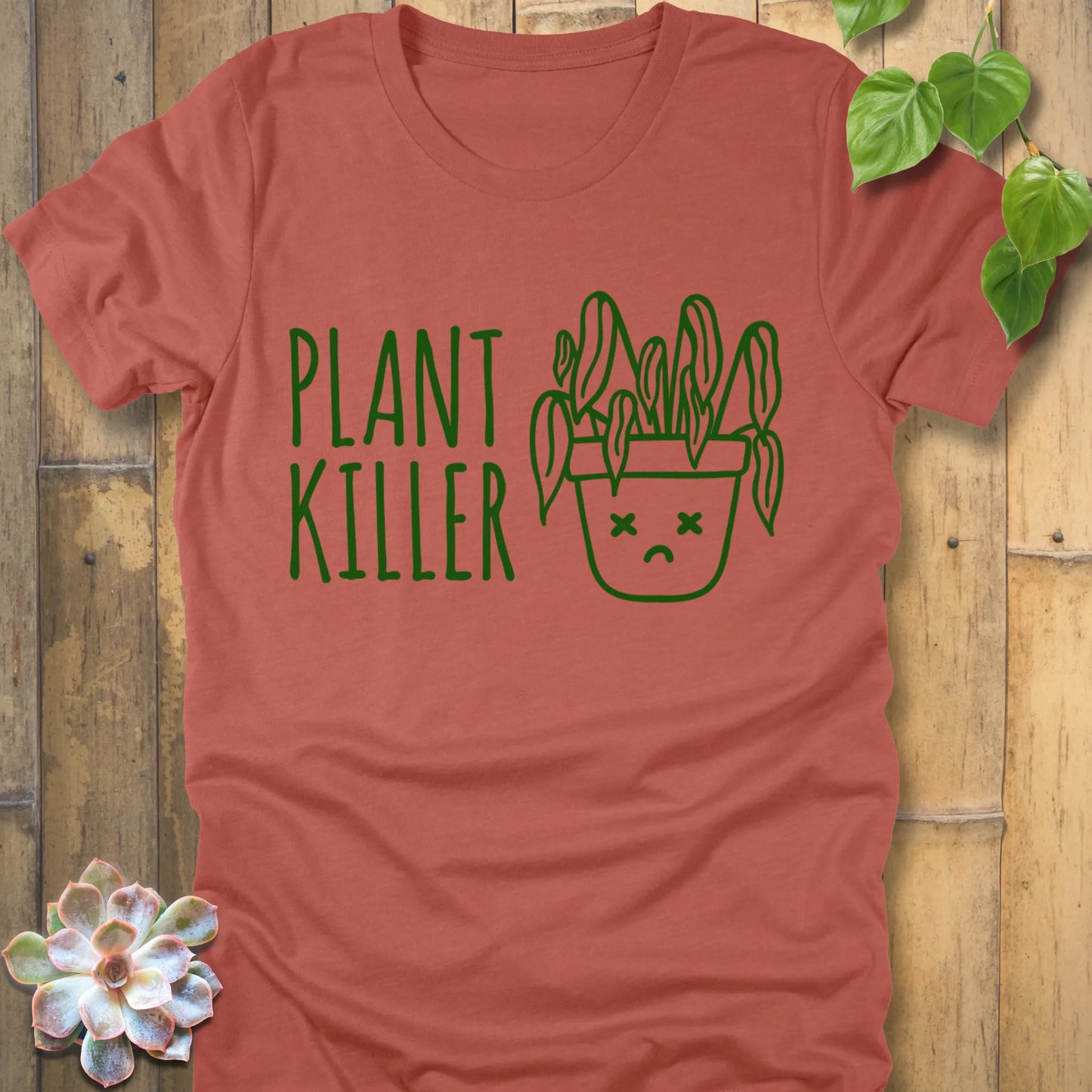 Heather Clay t-shirt featuring the design Plant Killer printed in green letters with a plant in an emoji pot 