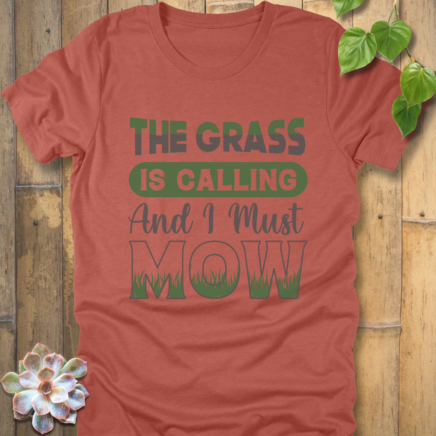 Heather Clay t-shirt featuring the design The Grass is Calling and I Must Mow in bold letters and with grass