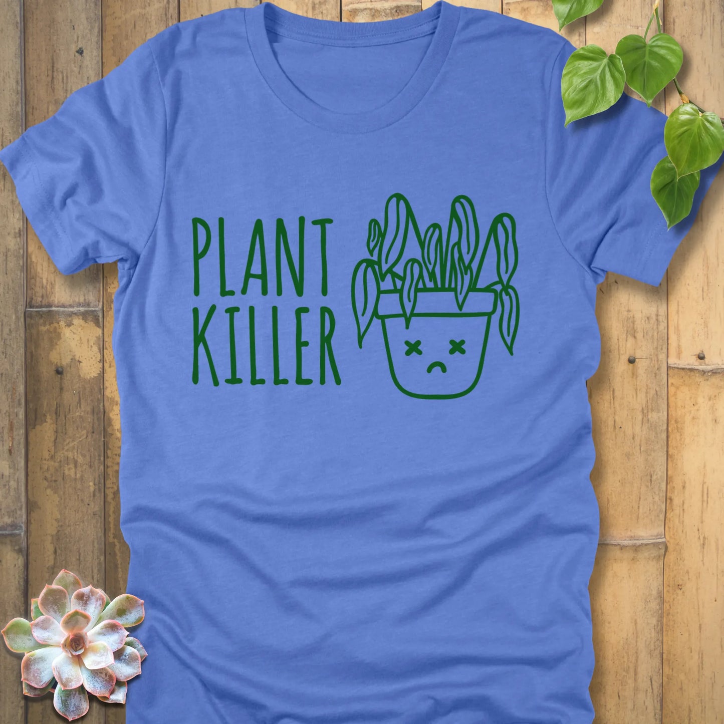 Heather Clombia Blue t-shirt featuring the design Plant Killer printed in green letters with a plant in an emoji pot 