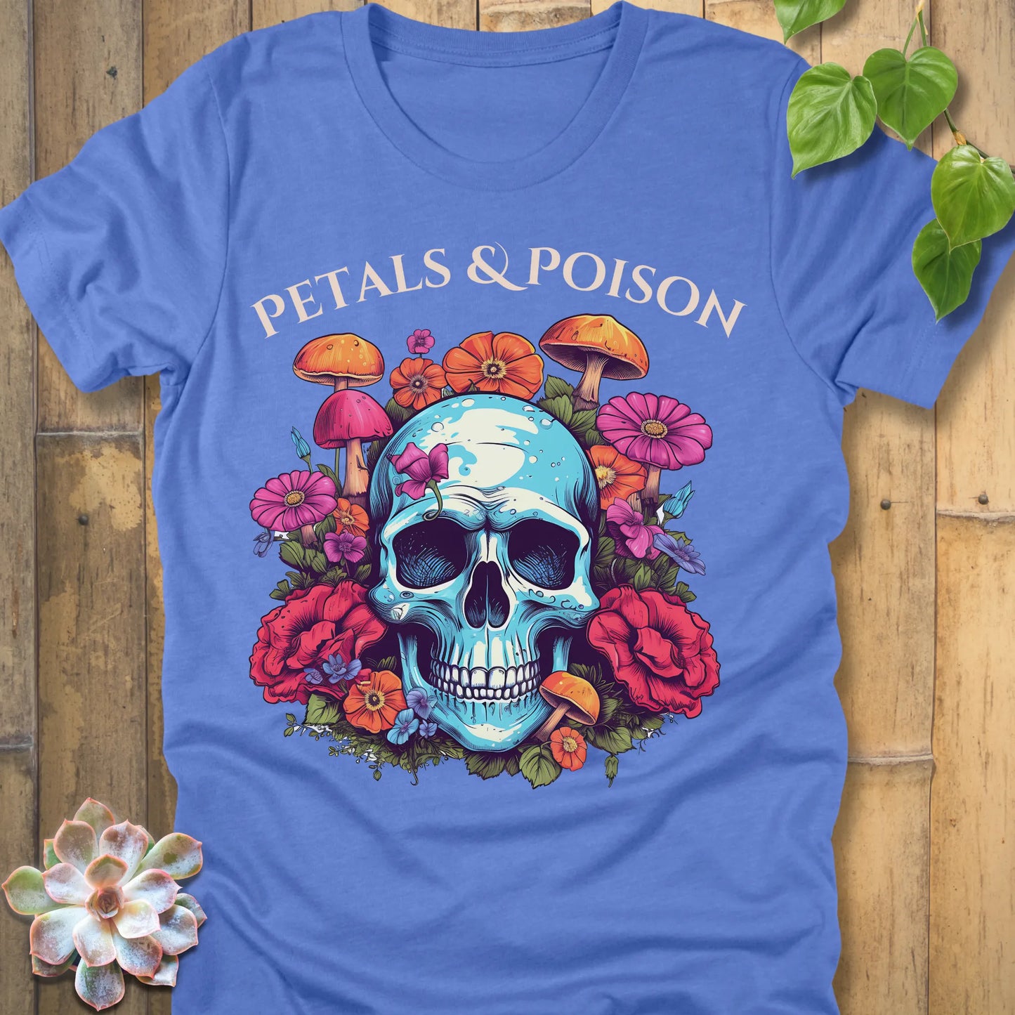 Heather Colombia Blue t-shirt featuring the design Petals & Poison printed in bold letters and a flowers, mushroom and skull